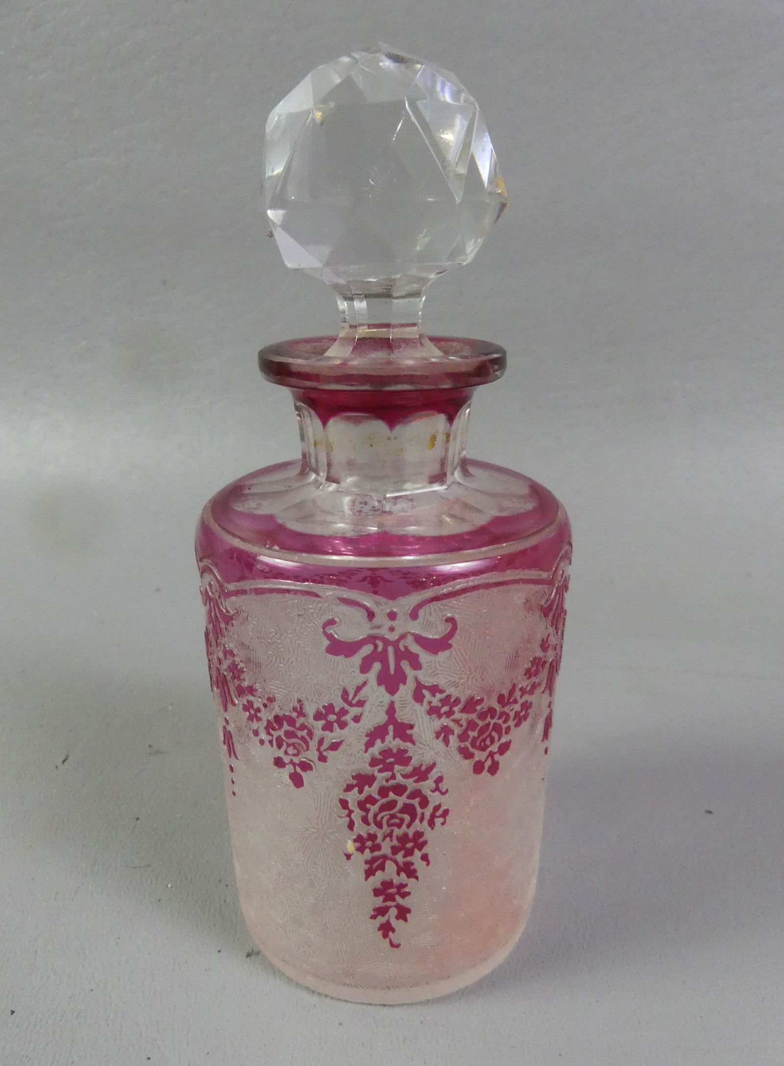 VAL ST. LAMBERT CAMEO PERFUME BOTTLE: Fine cranberry overlay, cameo acid etched perfume bottle signed Val St. Lambert (script). It has a floral design with faceted knob stopper. Excellent condition. 5.25 in tall and 2 in diameter. NOTE: