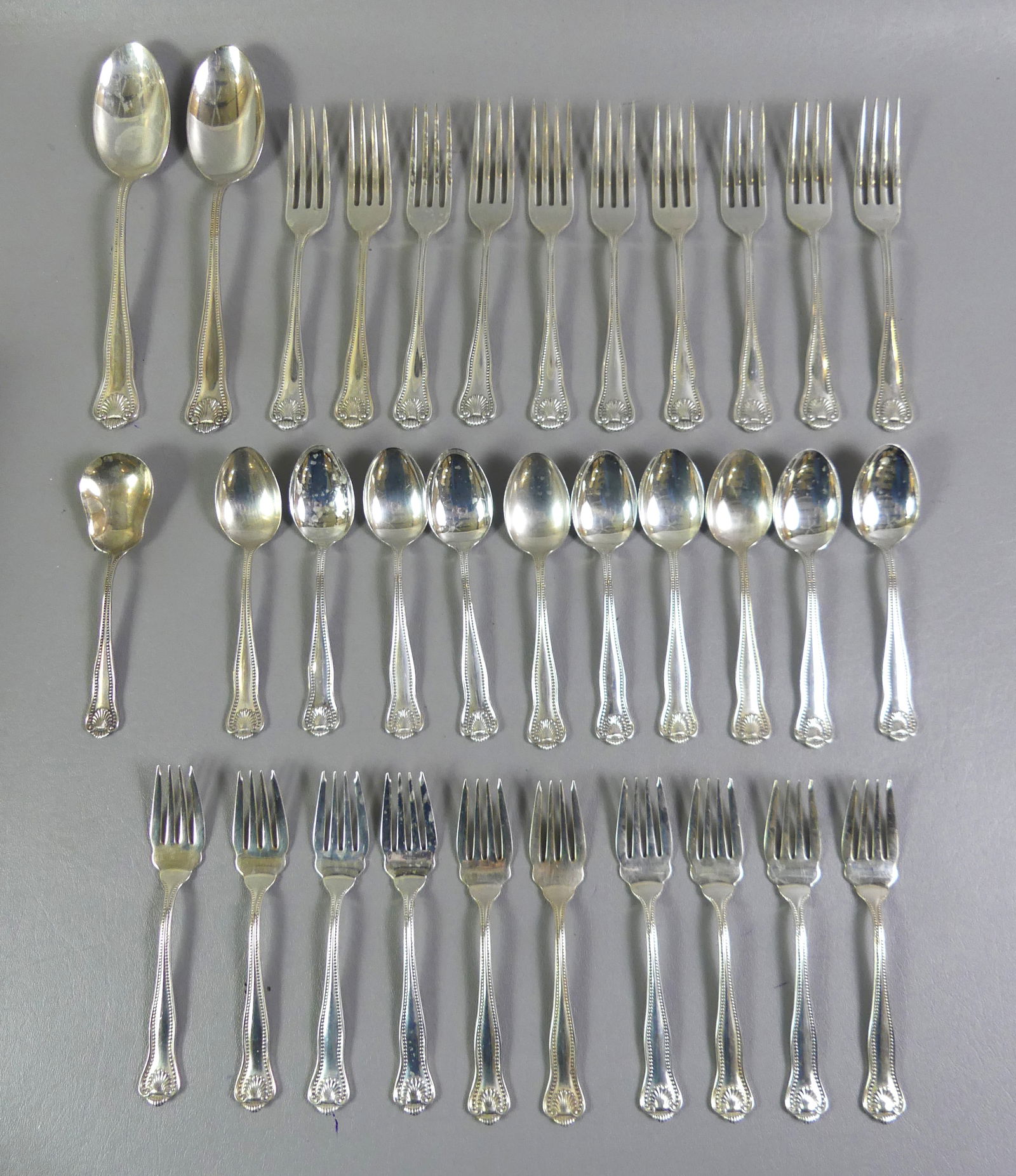 F. SMITH STERLING FLATWARE SET: Sterling silver flatware set by Frank Smith in a bead and shell design: 10 dinner forks, 10 luncheon forks, 10 teaspoons, sugar shell and pair of serving spoons. 53.25 ozt. NOTE: We can ship this item