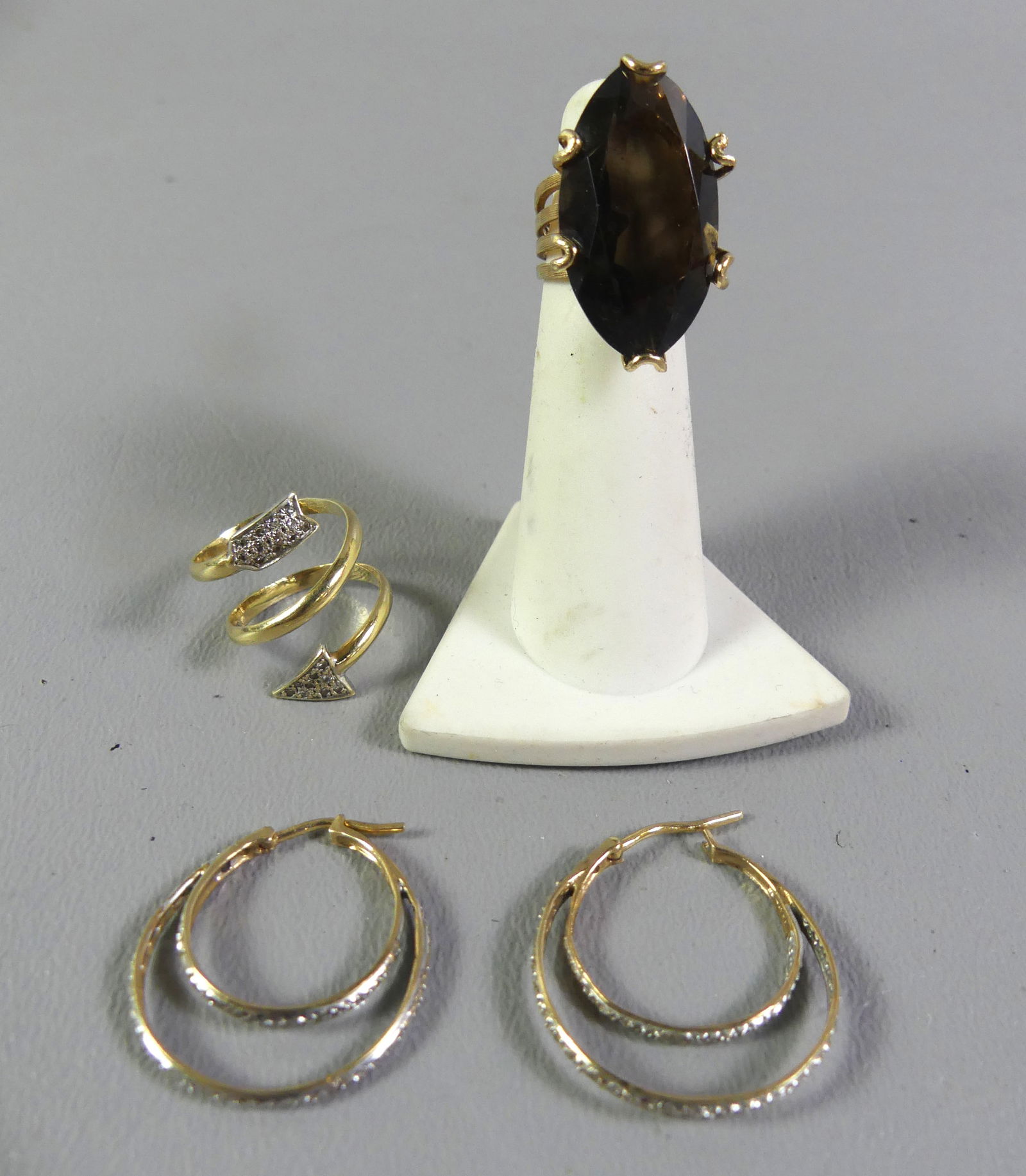 4 PIECES 14K GOLD JEWELRY: Lot 4 pieces of 14k gold jewelry: Smoky quartz ring, size 2.5 (that is correct), stone is one-inch high; pair of double hoop earrings with tiny diamonds; Size 4-5 wrap ring in arrow form with tiny dia