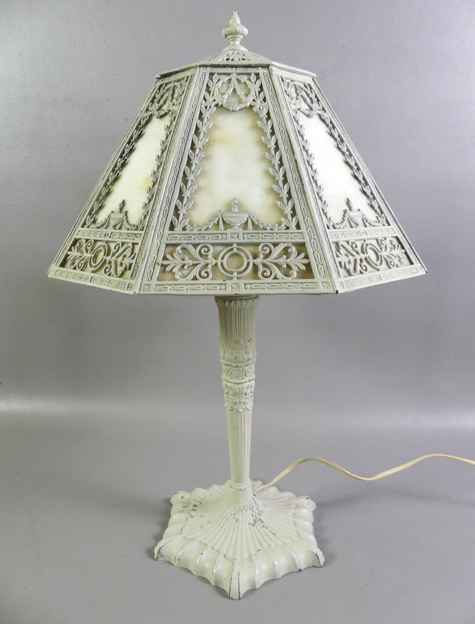 SLAG GLASS ELECTRIC PANEL LAMP: Circa 1920 electric table lamp with 8 panel slag glass conical shade and classical urn decoration. Painted metal, unsigned, 3 sockets. 22 in tall x 14 in diameter. Good condition, no damage, some