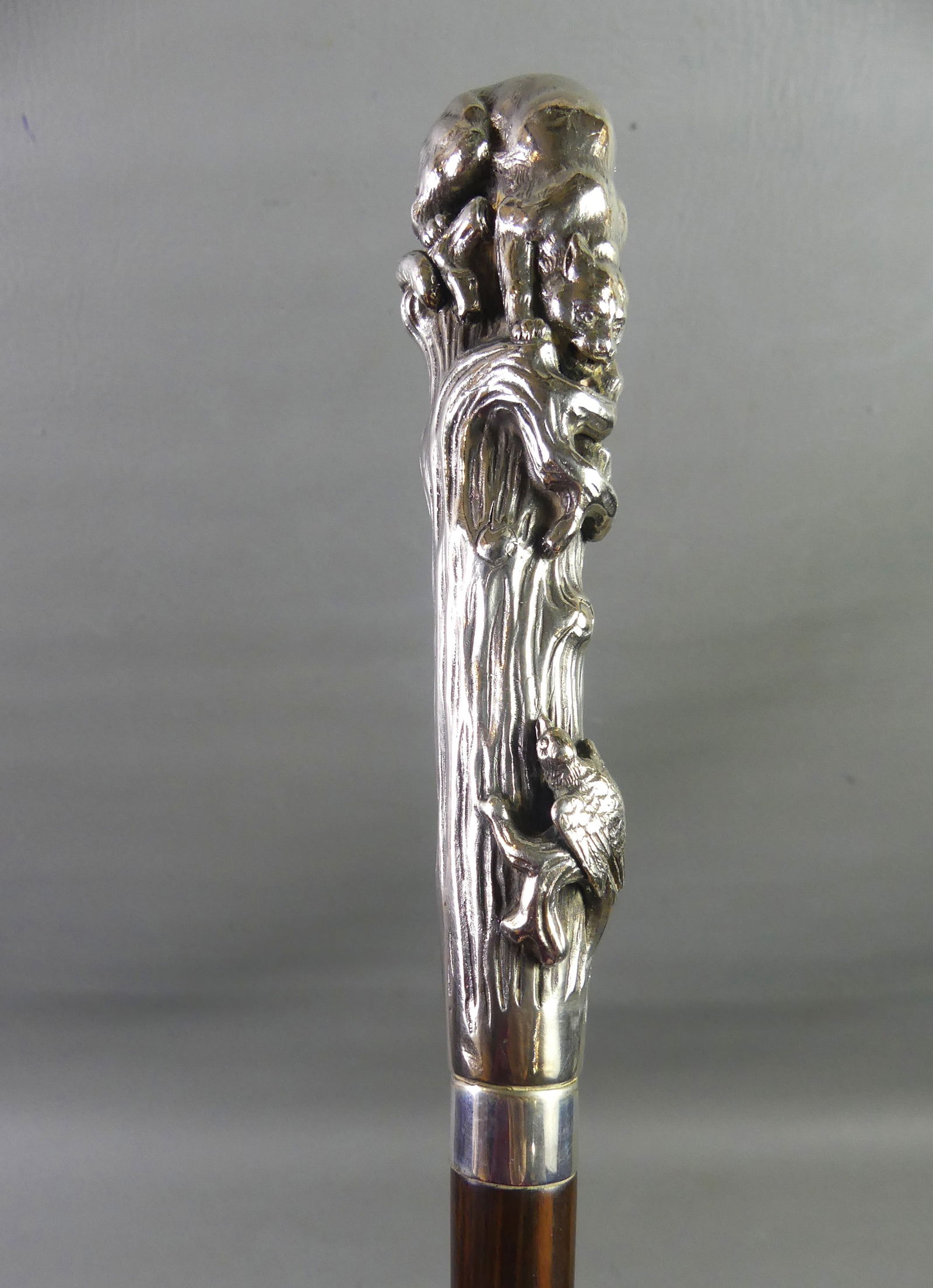 SILVER CANE - DOG CHASING BIRD: Antique silver handled cane with dog chasing a bird on stump. Sterling stamped collar, rosewood shaft. 36 in long, silver portion 6.5 in. NOTE: We can ship this item in-house