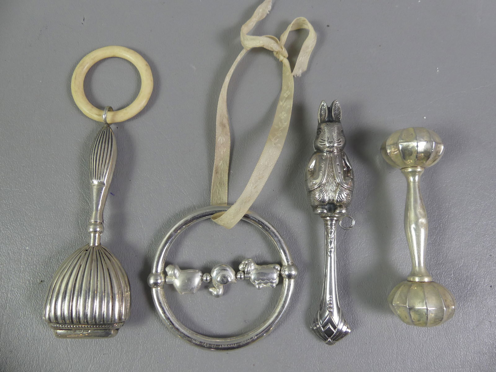 4 STERLING BABY RATTLES INCL.TIFFANY: Lot of 4 sterling silver baby rattles including rare Tiffany & Co. 2002 ring with 3 revolving animals, 3 in diam; rabbit; barbell shape; and striated with bone ring. Total 3.35 ozt. NOTE: We can ship