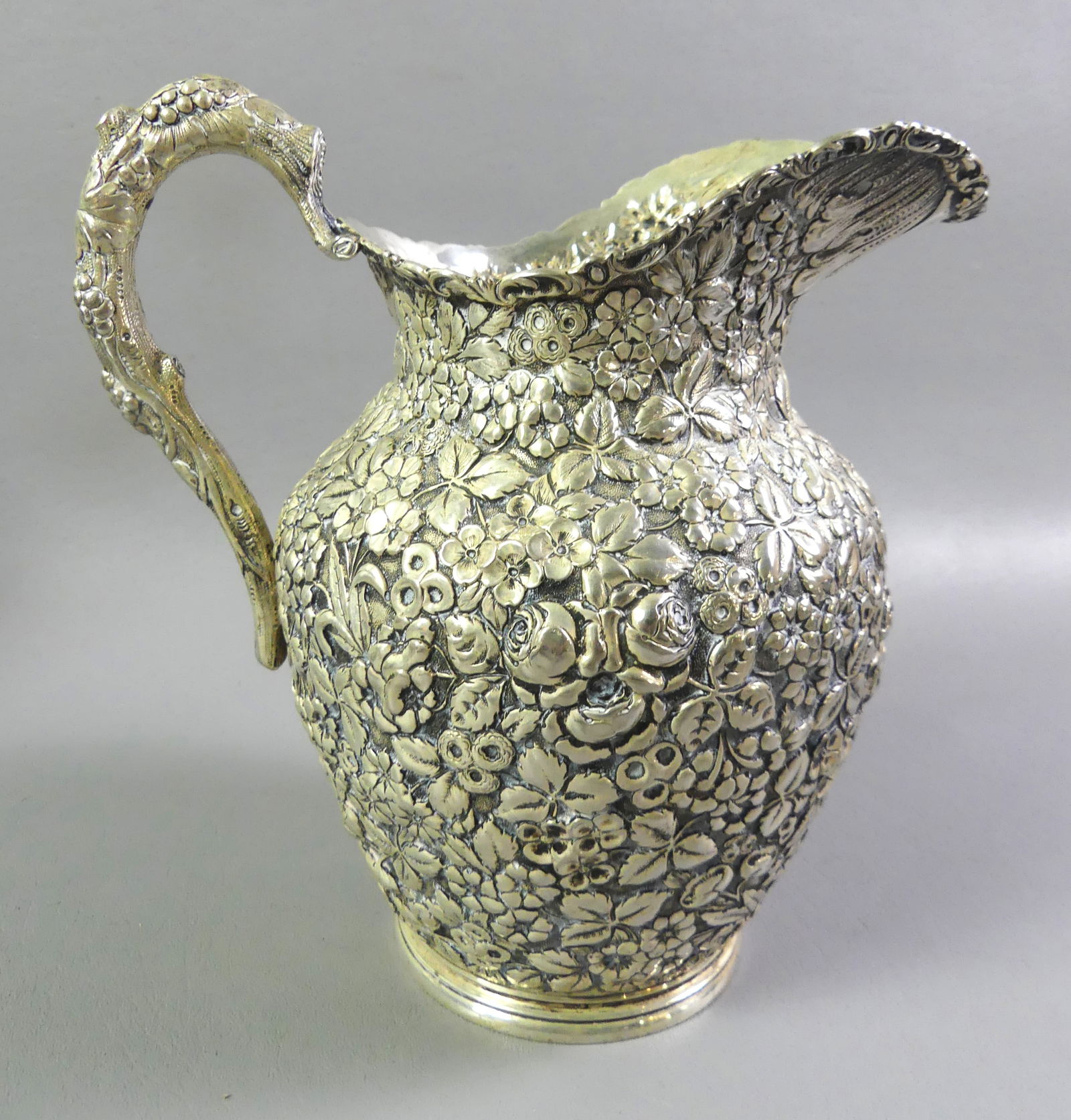 REPOUSSE STERLING PITCHER BY BALTIMORE: Elaborate antique sterling silver pitcher with allover floral repousse signed BSS Co (Baltimore Sterling Silver Co, predecessor of Stieff). Numbered 200, size 8 in tall and weighs 22.77 ozt. VG