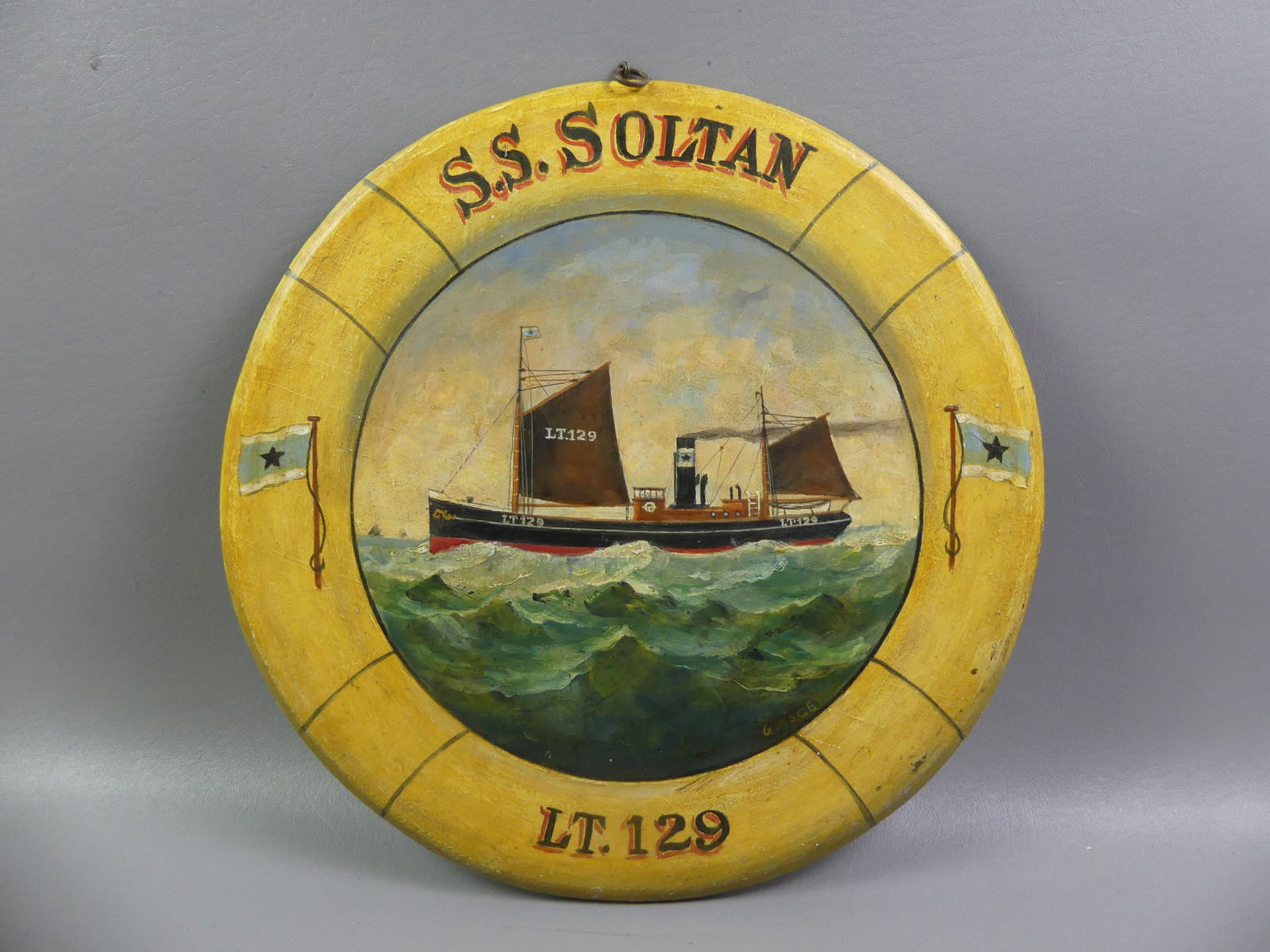 CIRCULAR PAINTING OF SHIP SIGNED MACEY: Round oil painting on wood panel (mimics a life preserver ring) of a tanker ship --SS Soltan L.T. 129 -- signed G. Macey. Back impressed Harbour Lights from Lowestoft Suffolk UK. 15 in diameter.