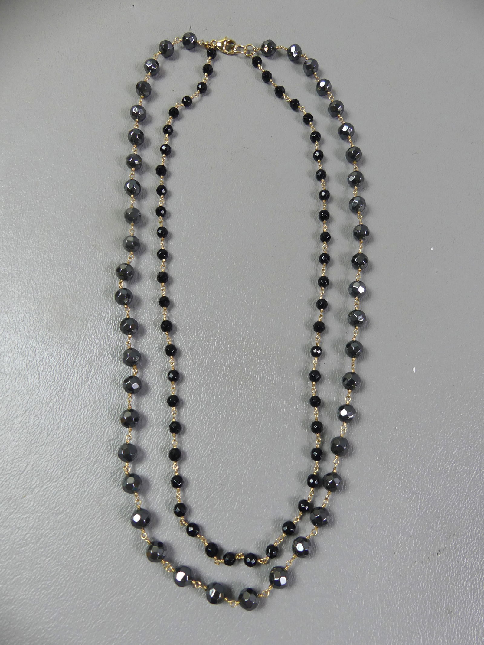 14K GOLD GEMSTONE DOUBLE NECKLACE: 14k gold layered double necklace with faceted hematite and black onyx gemstones. 18 and 16 in respectively. Weighs 21.2 dwt. NOTE: We can ship this item in-house.