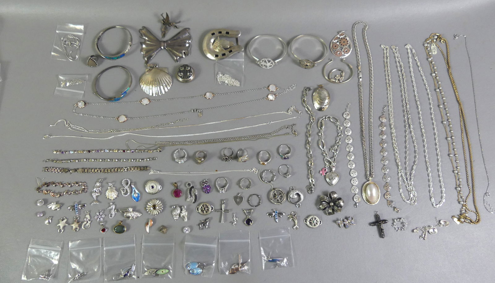 GROUP OF STERLING SILVER JEWELRY: Large lot of assorted sterling silver jewelry including a 3 inch horseshoe belt buckle; 12+ necklaces; 12+ bracelets; 10 rings; many earrings and pendants; 2.25 in scallop shell pendant; etc. About