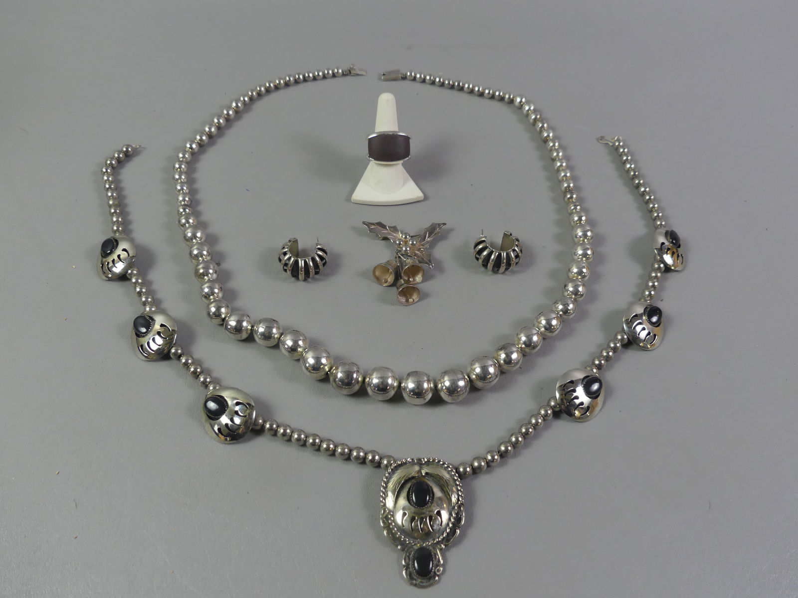 NATIVE AMERICAN & STERLING JEWELRY: Lot of sterling jewelry: 24 in Native American necklace with bear claw design, 2 in onyx pendant, and 6 enhancements; 32 in graduated bead necklace; pair heavy one-inch earrings; and size 7.5 ring