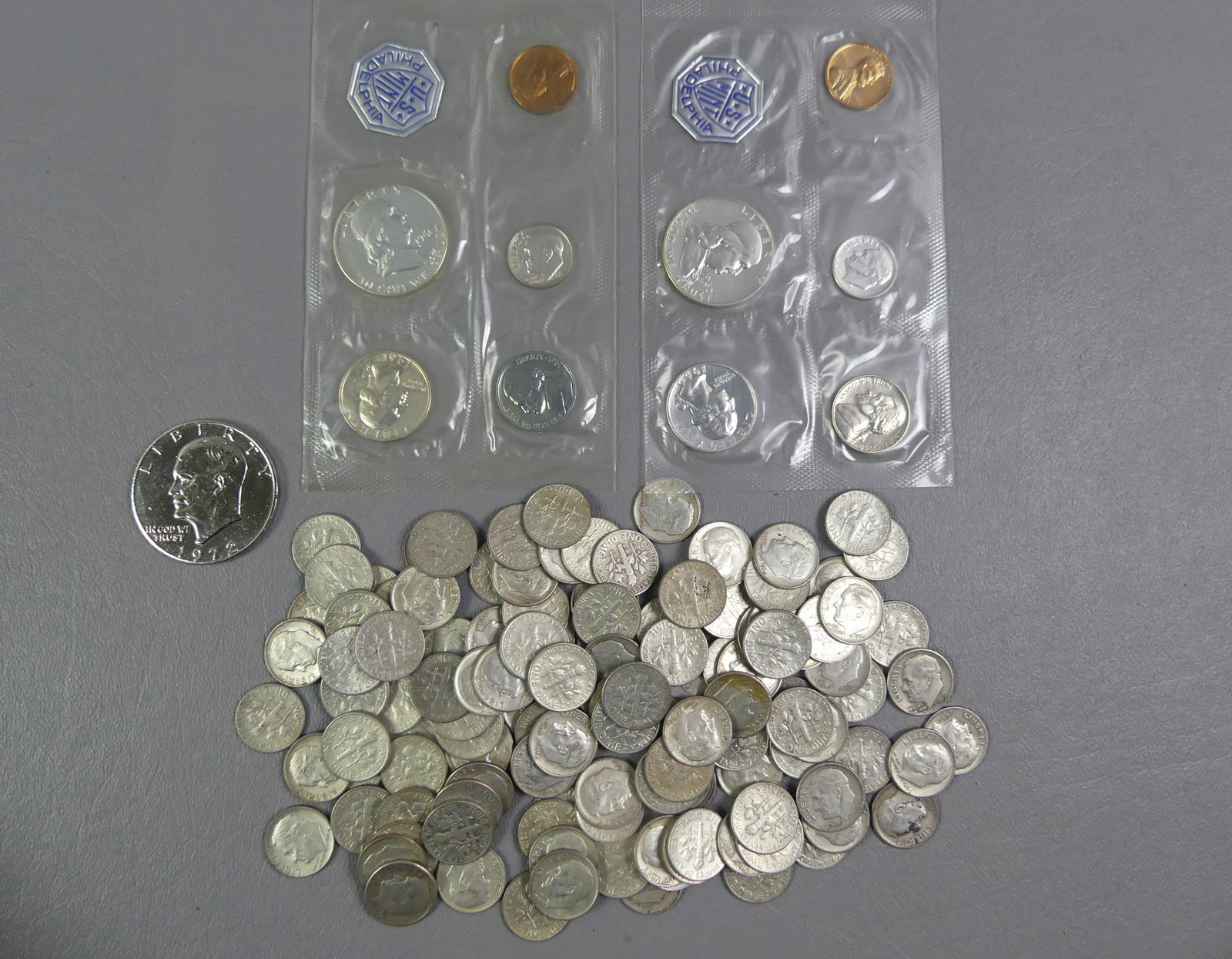 LOT OF US SILVER DIMES, ETC.: Large lot of old solid silver US dimes, ungraded, as found. Total weight 10.45 ozt. Plus a 1972 silver Eisenhower dollar and two Philadelphia Mint uncirculated 5 coin US sets in cellophane. NOTE: We c