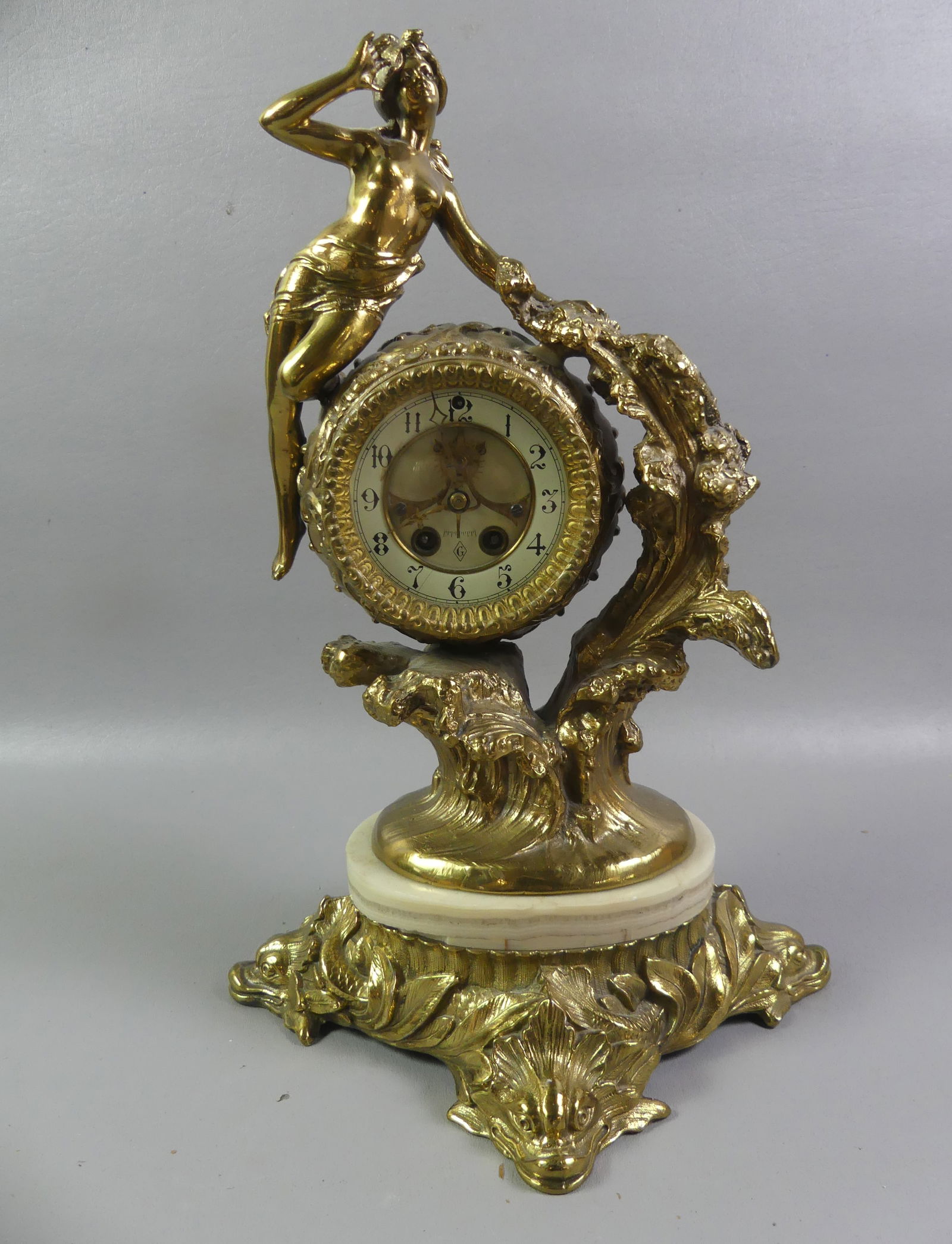 ART NOUVEAU GILT SHELF CLOCK - GILBERT: Old gilt metal Art Nouveau shelf clock with nude woman and dolphin base by Gilbert Clock Co of Connecticut. 3.5 in dial, 16 in tall and 11 in wide. Untested. NOTE: We can ship this item in-house.