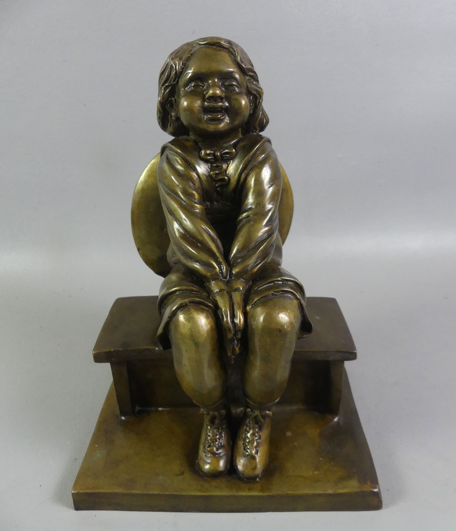 ANTIQUE BRONZE OF GIRL ON BENCH: Circa 1900 French bronze sculpture of a smiling little girl on bench. Unsigned. 11.5 in high x 8 x 6 in. NOTE: We can ship this item in-house.