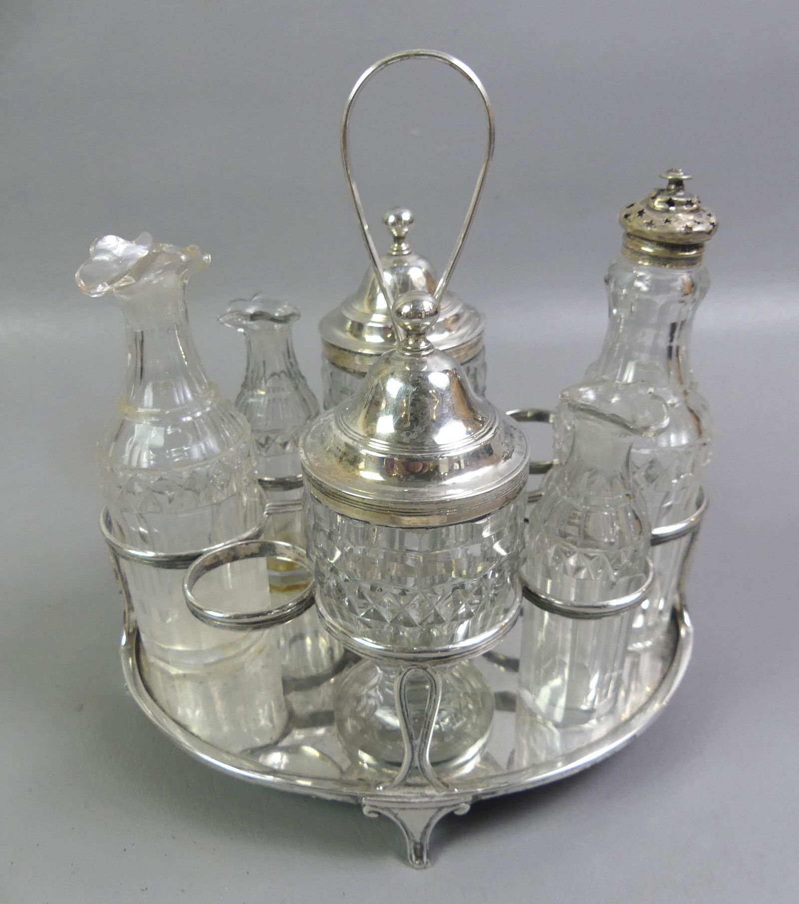ENGLISH STERLING & CUT GLASS CASTOR SET: Georgian sterling silver 6 bottle castor set (2 missing) with fine cut glass containers with polished pontils (couple small chips to 2 bottles missing stoppers). Hallmarks for London 1804 by maker