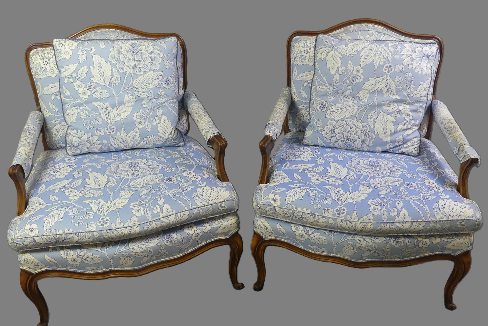 PAIR OLD FRENCH BERGERES - ARMCHAIRS: Pair of old Louis XV style upholstered bergere chairs with pillow. Blue floral upholstery with protectant fabric sleeves on arms (velcro closures). 30 in wide and 25 in deep. Good condition.