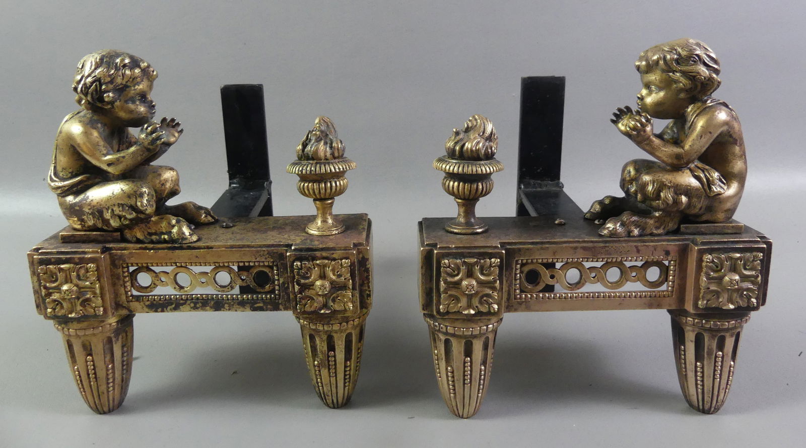 PR. FRENCH BRONZE FIRE DOGS: Pair of antique French bronze fire dogs in the form of a young Pan god with flaming urn. 10 in tall x 8.5 x 8.5 deep. NOTE: We can ship this item in-house.