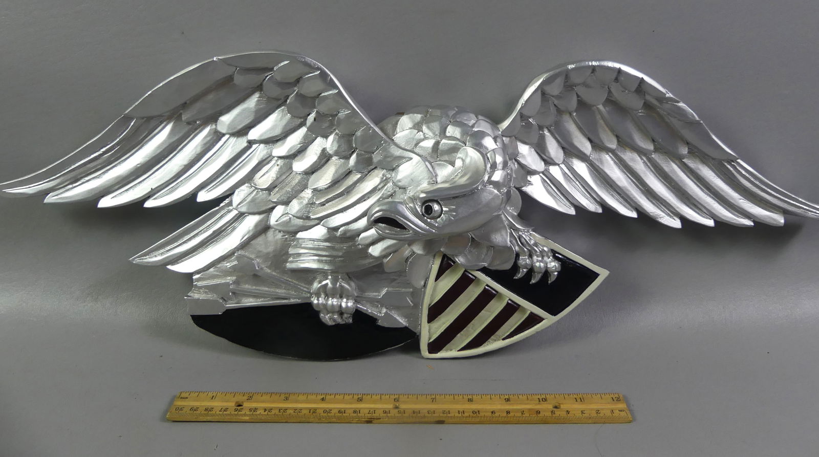 CARVED WOOD EAGLE PLAQUE: Modern carved and painted wood American eagle wall plaque. 25 in long and 9 in high. Unsigned