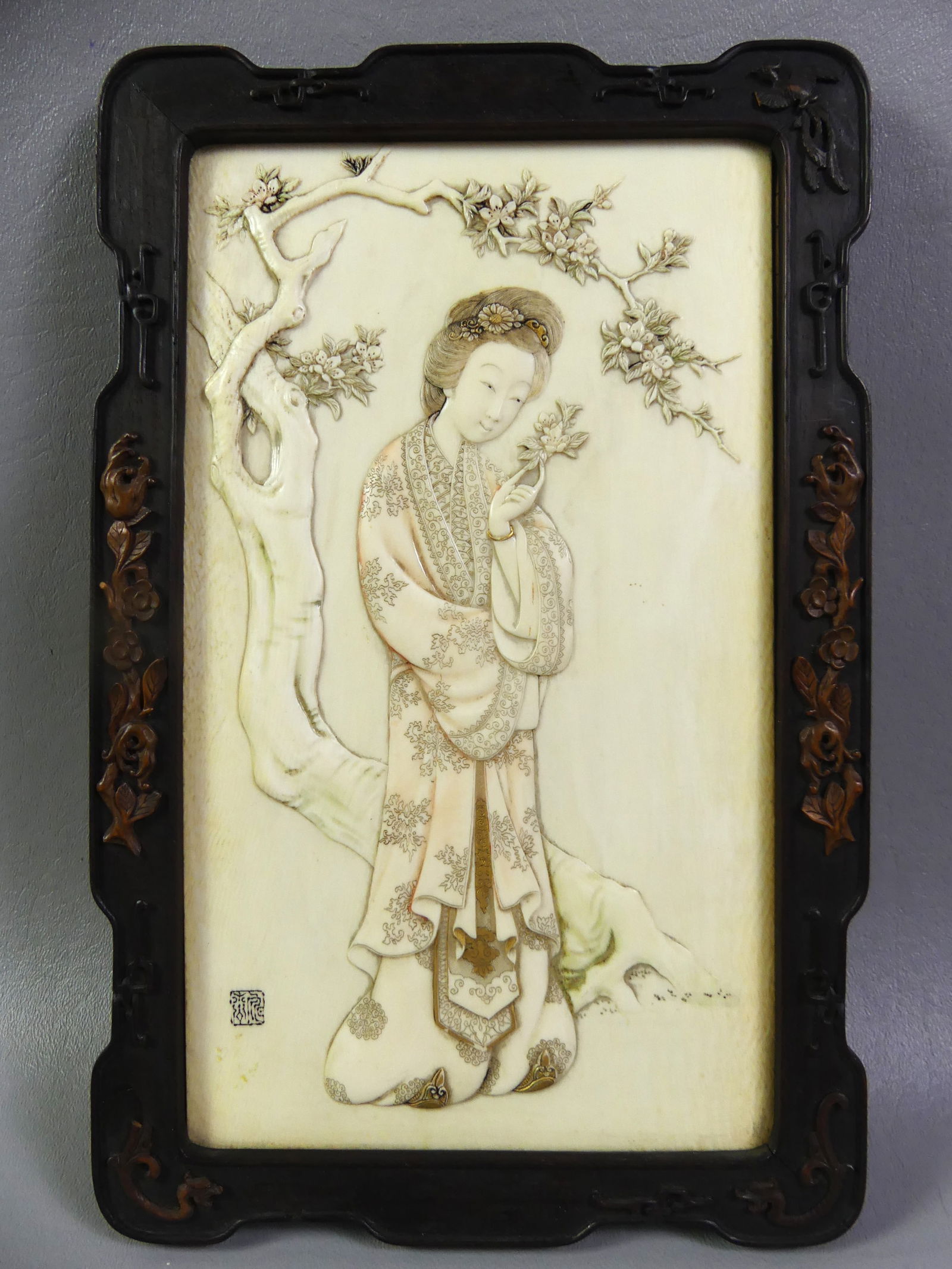ANTIQUE CHINESE CARVED PLAQUE - NOBLE WOMAN: Exquisite 19th century Chinese carved and polychromed bone wall plaque depicting a noble woman holding flower beneath a tree. Signed with Chinese seal in lower left. 9.25 x 5.5 inches, framed 11 x 7