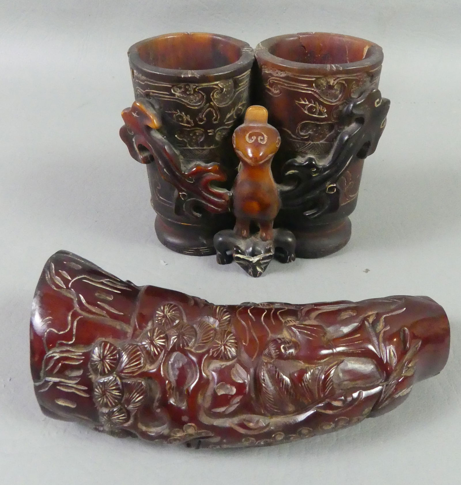 2 CHINESE CARVED HORN CUPS: Two 19th century (or earlier) Chinese carved horn items: 5.5 in libation cup; and a double champion cup (cracks) 4 x 3 x 3.75 inches. Carved with figures, flora, and large bird. The champion cup was