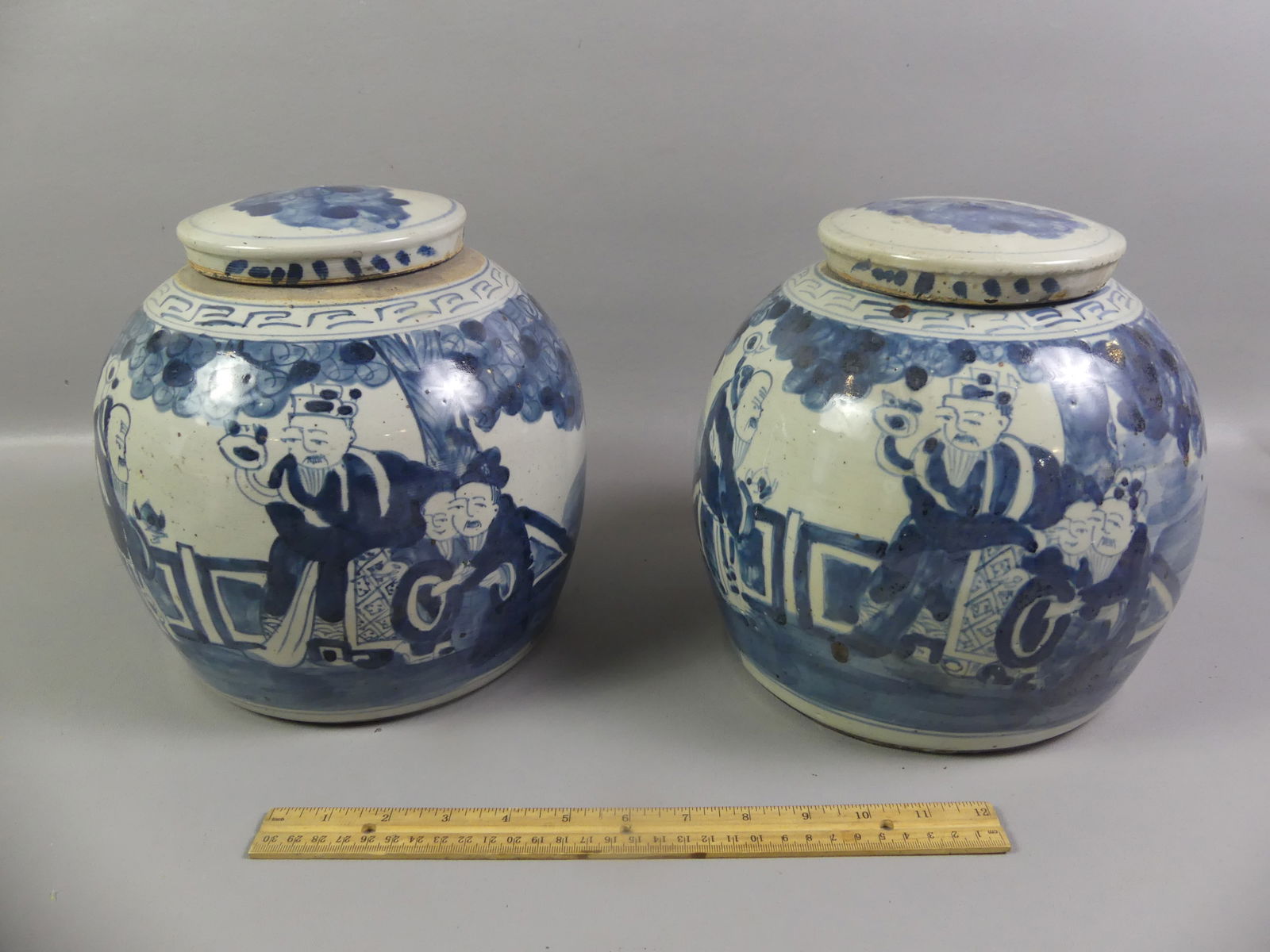 PAIR CHINESE GINGER JARS - GENRE: Pair of Chinese blue and white covered ginger jars with genre scenes on front, 9 x 8 inches. Unsigned. Both good condition. NOTE: We can ship this item in-house.