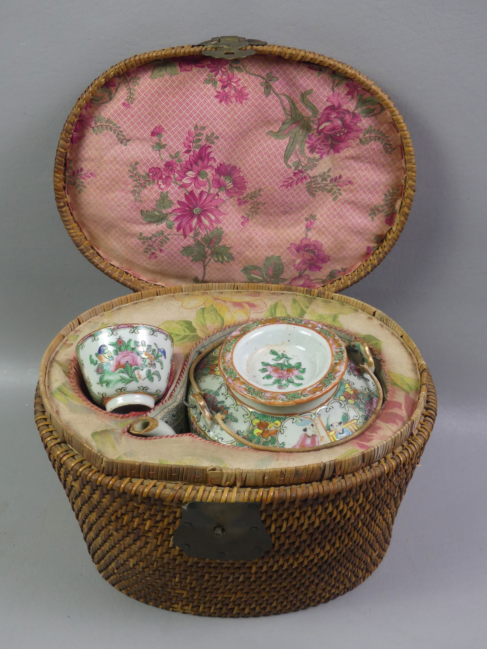 CHINESE ROSE MEDALLION TEAPOT IN BASKET: 19th century Chinese Rose Medallion lidded drum teapot and handleless cup in original woven basket. Pot has a substantial chip on lip. Unsigned. Pot is 6 in tall. NOTE: We can ship this item in-house.
