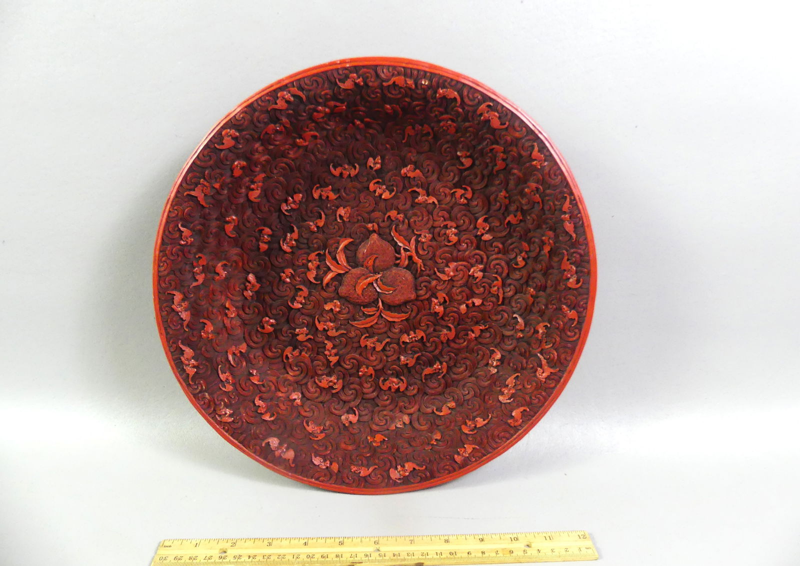 CHINESE CINNABAR BOWL - SIGNED: Finely carved old Chinese cinnabar shallow bowl with carved bats, clouds, and pomegranite center. 13 in diameter and 2.5 in deep. Signed on bottom with seal and Asian characters. VG condition. NOTE: