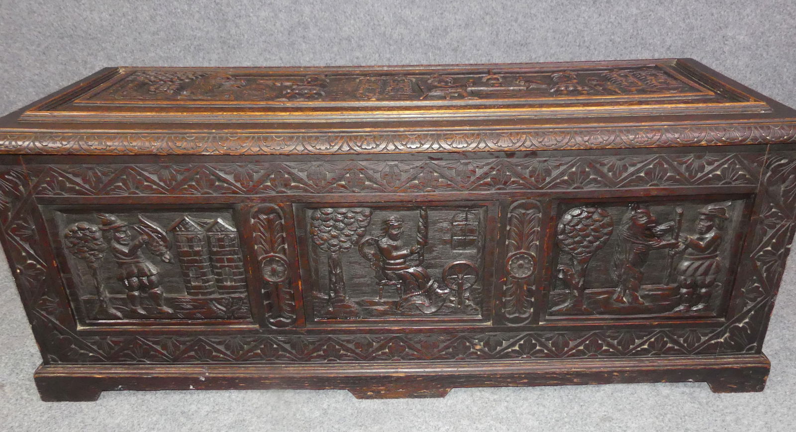 VICTORIAN CHEST -MEDIEVAL GENRE SCENES: Victorian deeply carved lift-top English chest with Medieval genre scenes including hunters, men in pub, man spinning yarn, etc. 4 ft long x 19 x 18 inches. Good condition.