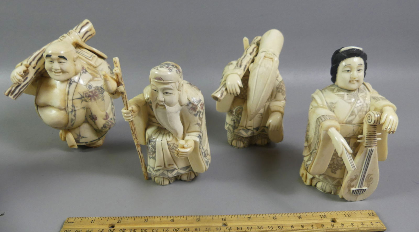 4 JAPANESE CARVED FIGURES: Set of 4 antique Japanese carved bone chunky figures, 6.5 x 4.5 x 4 inches: woman with lute, man with staff, and 2 men carrying mat and a sack. Three are signed. Good condition. NOTE: We can ship