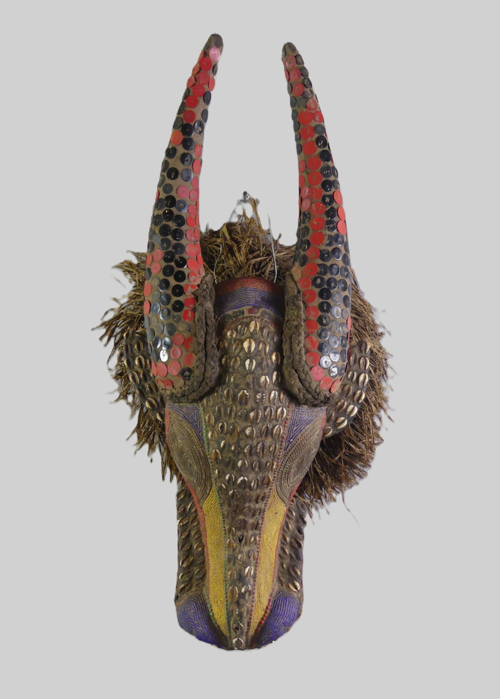 AFRICAN HORNED ANIMAL MASK: Vintage African mask of a horned animal made from wood, beads, shells, and straw. 31 x 15 x 12 inches. NOTE: We can ship this item in-house.
