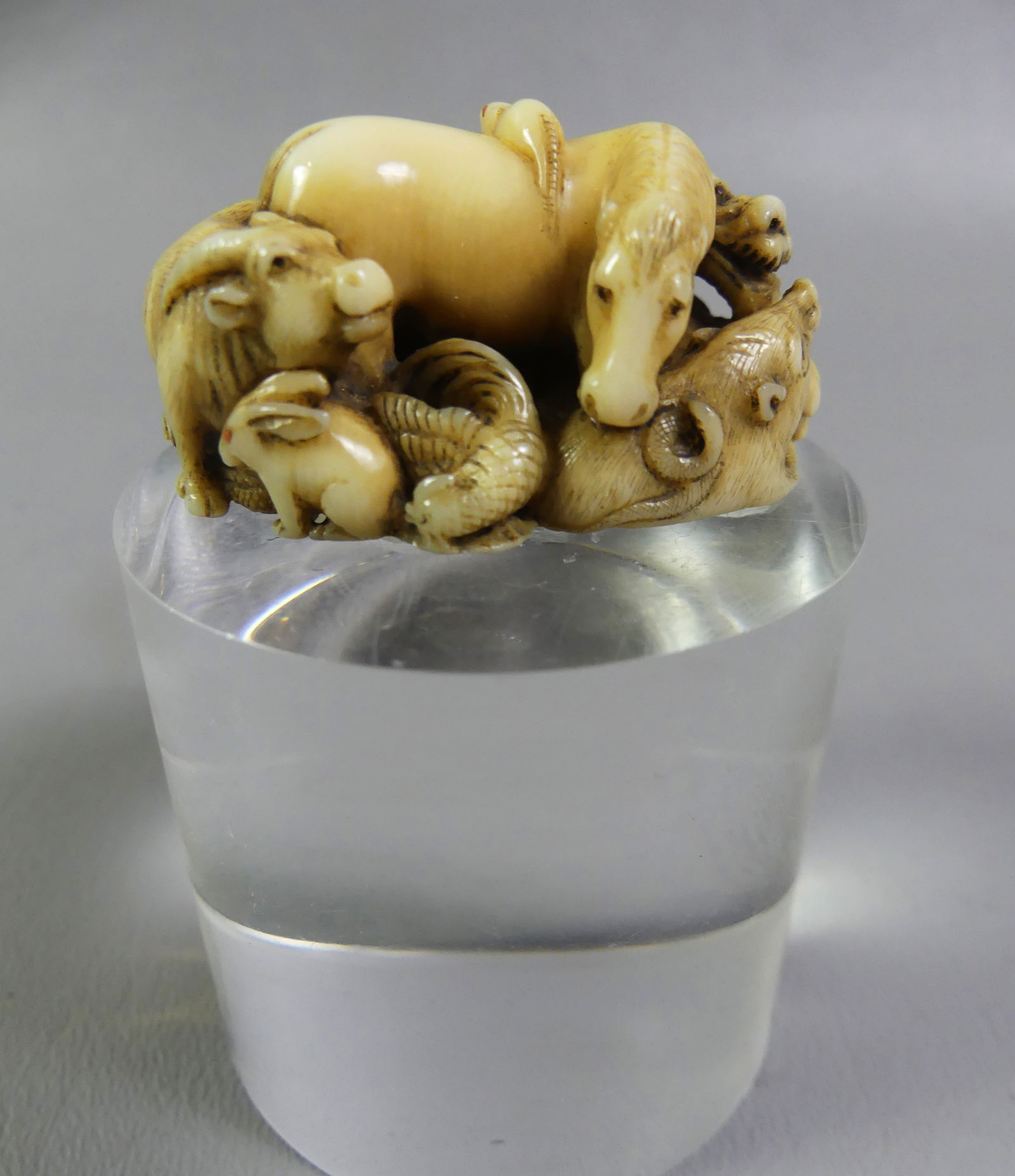 JAPANESE MINIATURE ANIMALS FIGURINE: Antique Japanese carved miniature animal group, mounted on lucite stand, signed. 1 x 1.75 x 1.32 in, stand is 2 in tall. Ex-collection of Andrew C. Ware.NOTE: We can ship this item in-house.