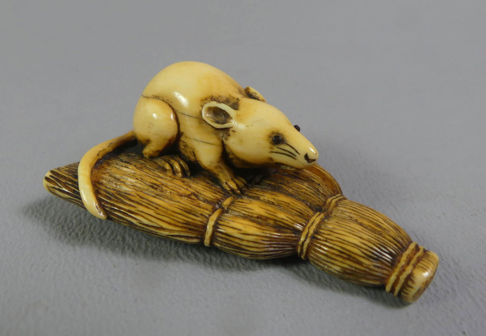 JAPANESE NETSUKE - RAT ON BROOM: Fine antique Japanese netsuke depicting a rat on a straw broom. Unsigned. 2 x 1.5 x .75 in high. Ex-collection of Andrew C. Ware.NOTE: We can ship this item in-house.