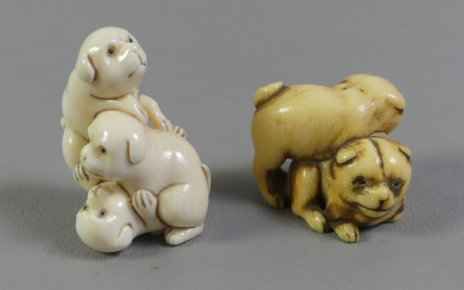 2 JAPANESE NETSUKES - DOGS: Lot of 2 antique Japanese netsukes: 3 playful puppies with inset abalone signature plaque, 1.5 x 1 in; and 2 dogs wrestling, signed 1 x 1.25 inches. Ex-collection of Andrew C. Ware. NOTE: We can