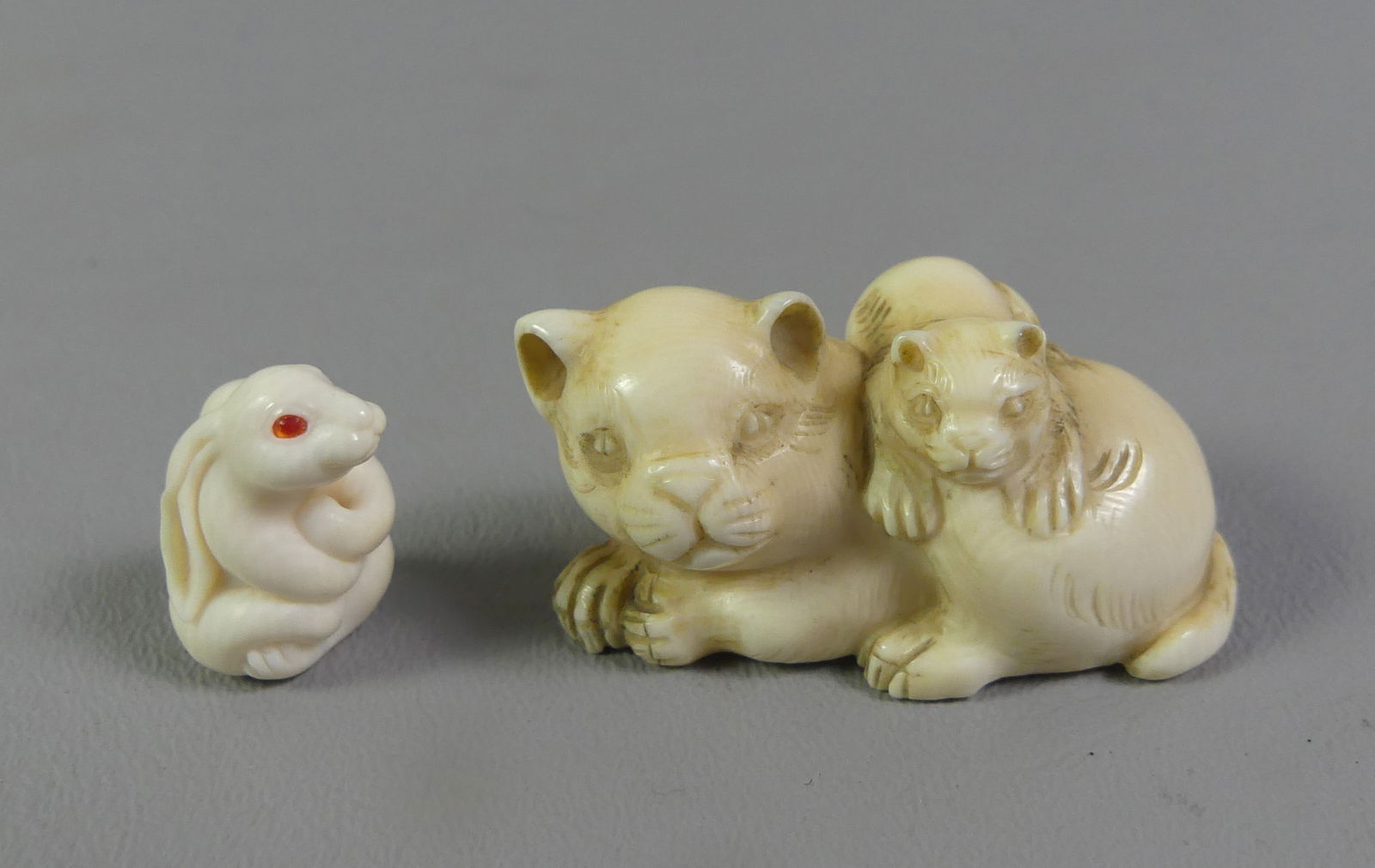 2 JAPANESE NETSUKES - CATS & BUNNY: Lot of 2 Japanese netsukes: 2 x 1 inch of rabbit with red eyes, unsigned; and 2 cats playing, signed. Ex-collection of Andrew C. Ware. NOTE: We can ship this item in-house.