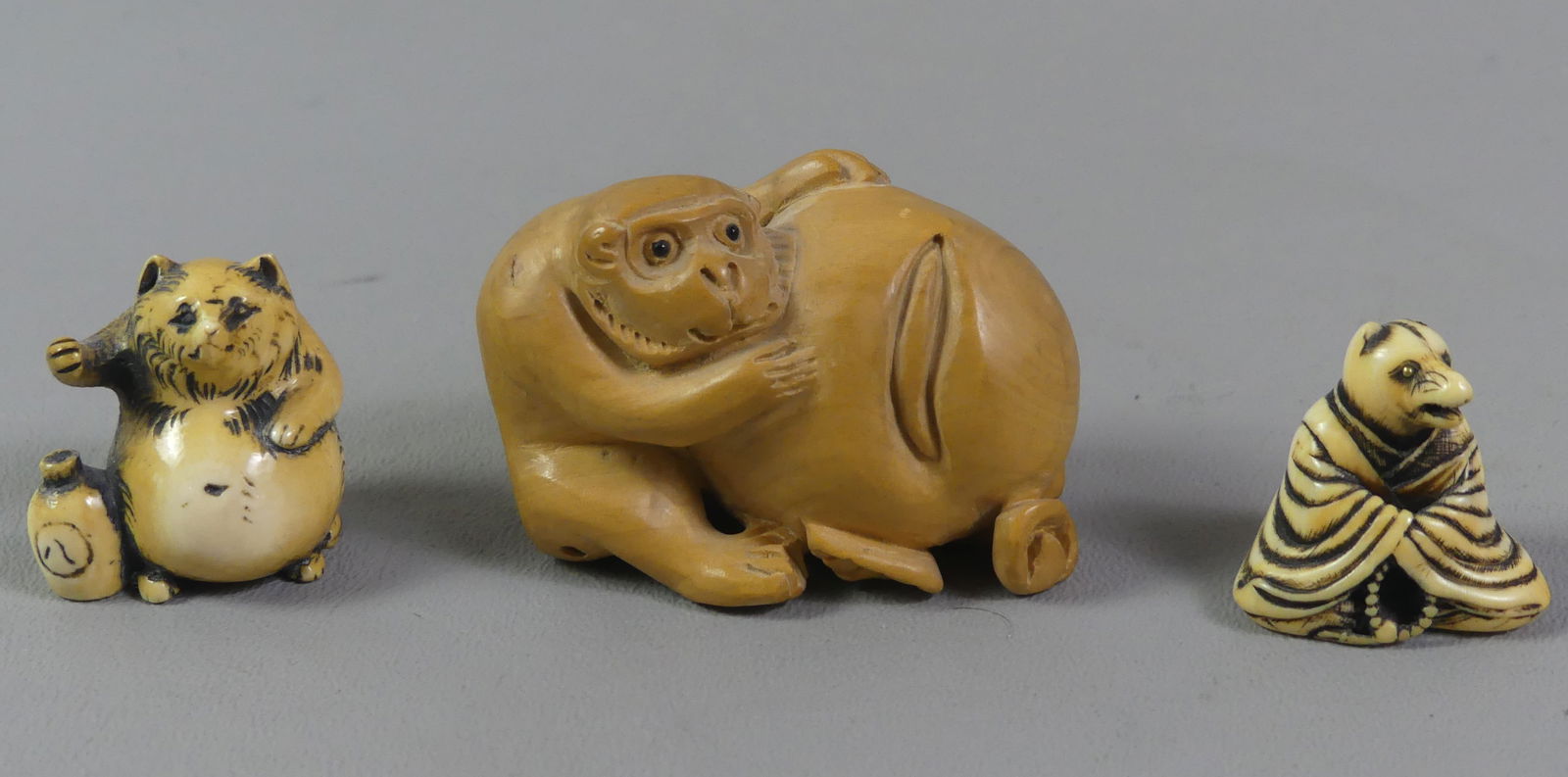 3 JAPANESE NETSUKES - ANIMALS: Lot 3 Japanese antique carved netsukes: carved wood of monkey holding a large nut, signed, 2 x 1.5 in; fox with jug, signed, 1.25 x 1 in; and seated fox in robe, 1 x 1 inch. Ex-collection of Andrew
