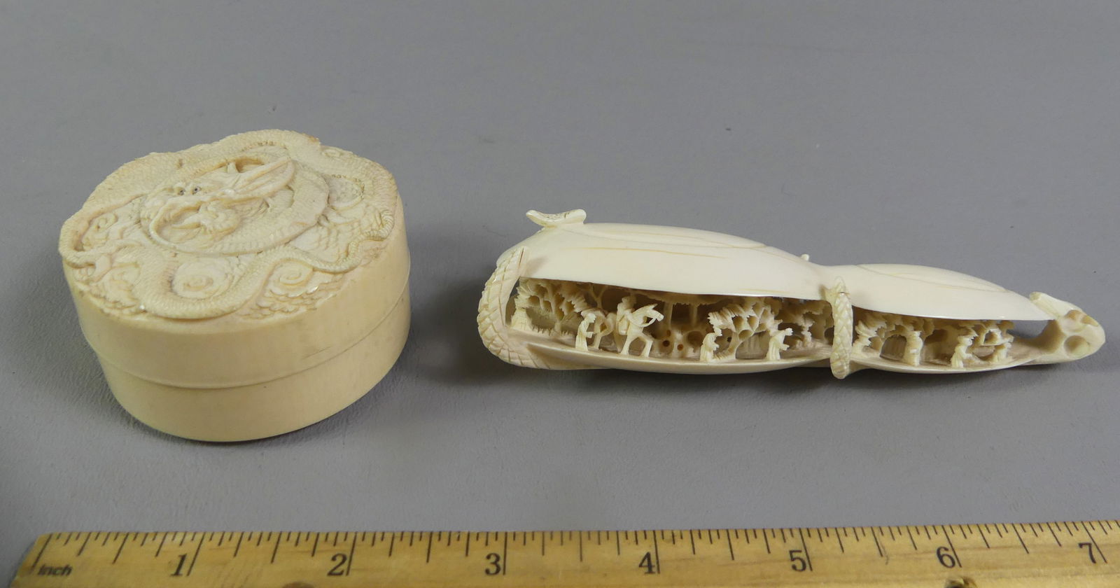 ASIAN CARVED CLAM SHELL & TRINKET BOX: Lot of 2 Asian carved bone items: doulbe clam shell with many figure in a village, 5 in long x 1 x 1.5 in; and round trinket box with carved dragon on lid, 2.5 x 1.25 in high. NOTE: We can ship this