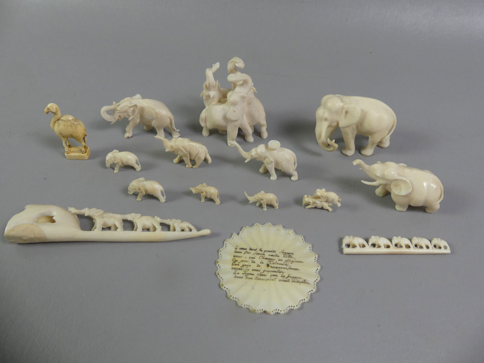 ASIAN CARVED ELEPHANTS LOT: Lot of mostly carved bone elephants to 2.5 in high. Also a camel stamp and circular carved 2.25 in plaque with French script. Total 15 pieces. NOTE: We can ship this item in-house.