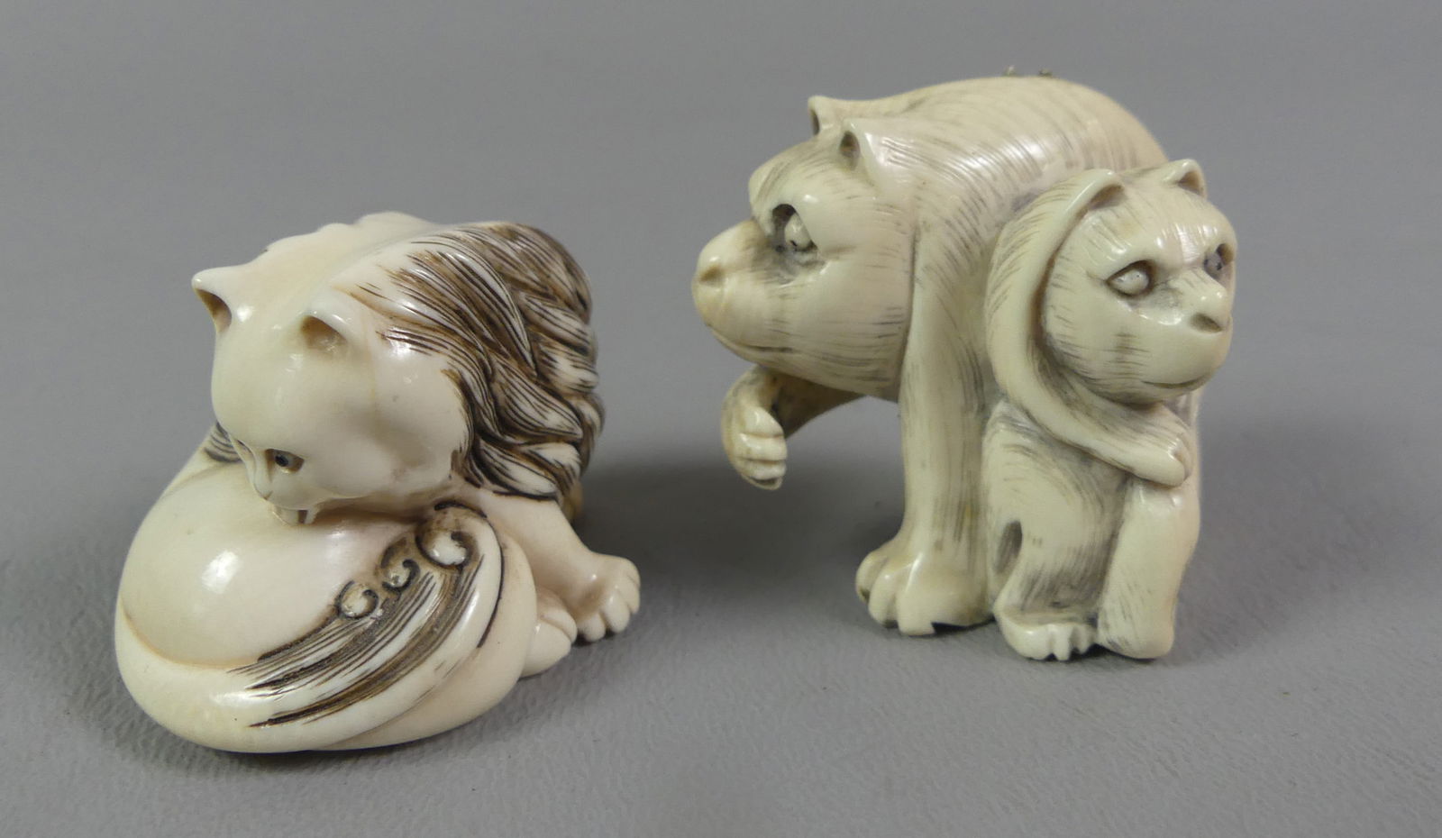2 JAPANESE NETSUKES - CATS: Lot of 2 antique carved Japanese netsukes: 2 cats, signed, 1.5 x 1.5 in; and cat cleaning her haunches, 1 x 1.5 in. NOTE: We can ship this item in-house.