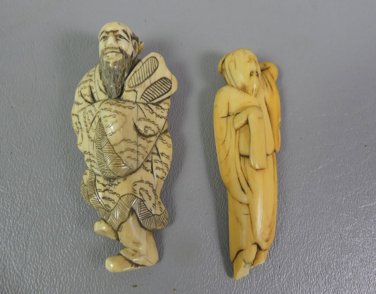 2 JAPANESE NETSUKES - MEN: Lot of 2 antique carved Japanese netsukes: 3 in reclining man (chip to foot) and man holding a fan, 3 in. NOTE: We can ship this item in-house.