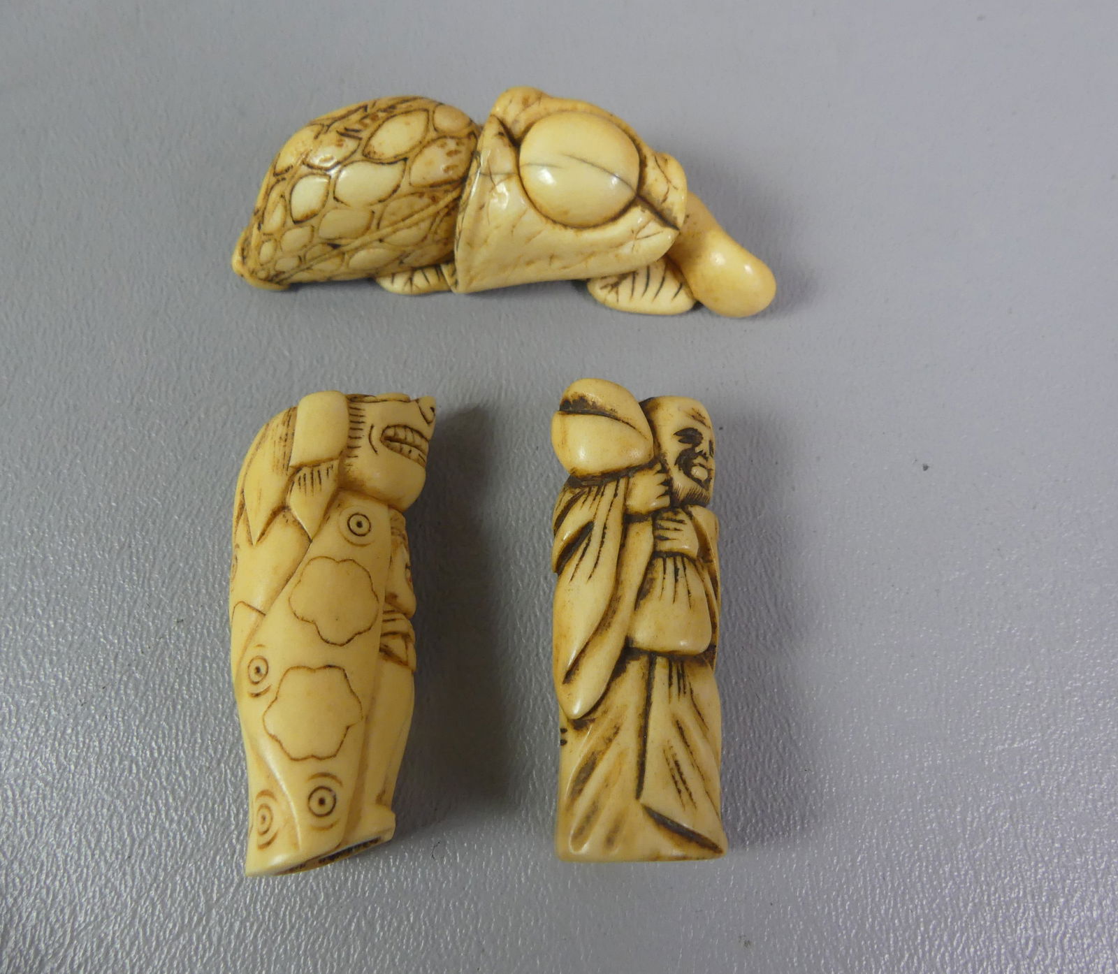 3 JAPANESE NETSUKES: Lot of 3 antique carved Japanese netsukes: man in costume and a man in robe, both 2 in long; 2.75 carved branch with nut. NOTE: We can ship this item in-house.