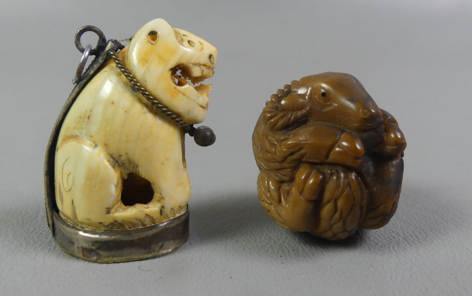 2 JAPANESE NETSUKES - RAM & LION: Lot of 2 antique carved Japanese netsukes to 1.25 in: circular gemstone (?) carving of a ram; and lion with silver necklace mount. Both unsigned. NOTE: We can ship this item in-house.