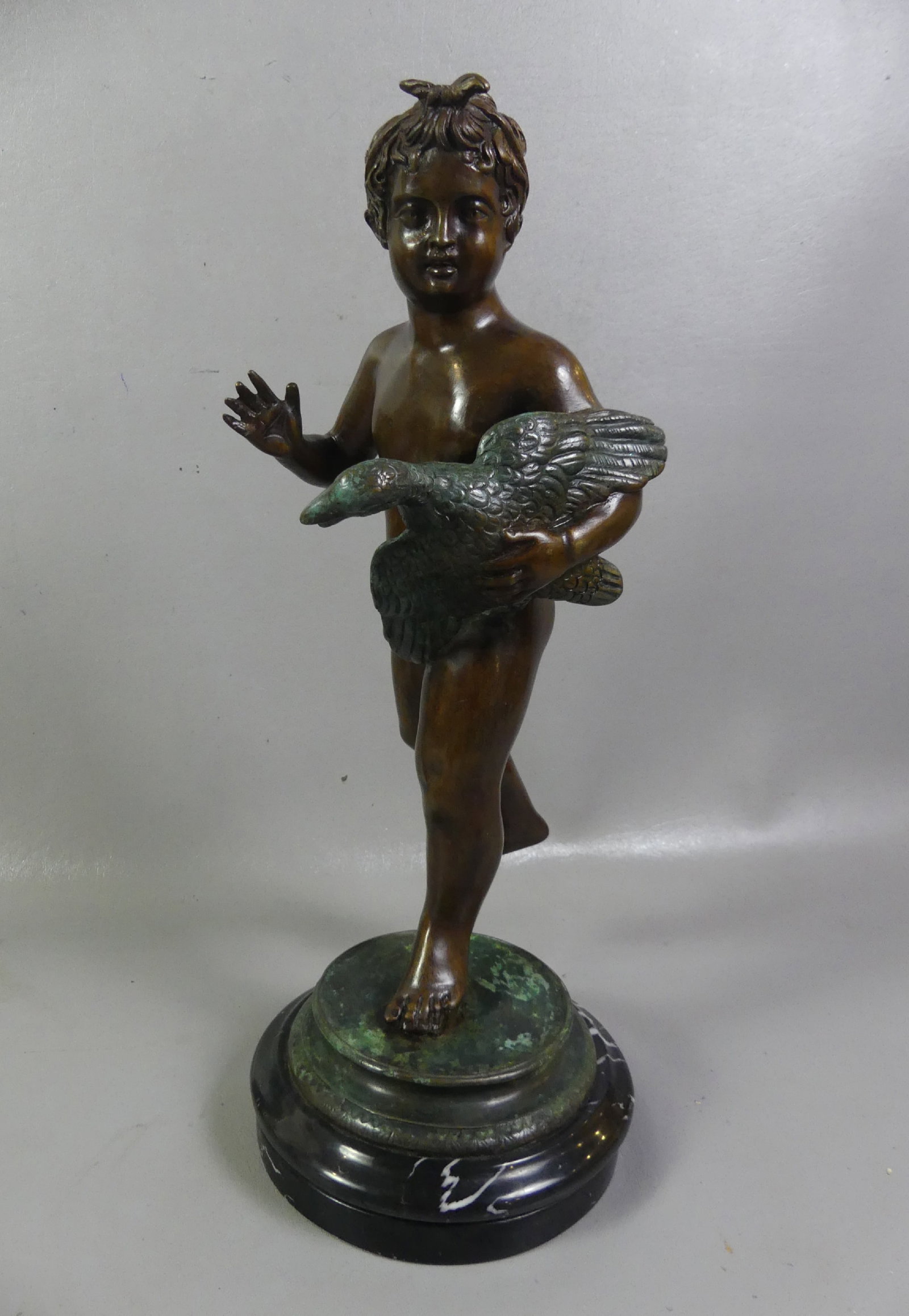BRONZE NUDE BOY HOLDING GOOSE: 20th century bronze sculpture of a nude boy holding a goose. Parcel verdigris patina with marble base. 18 in tall x 6.5 in diameter. Unsigned. Note: We can ship this in-house.