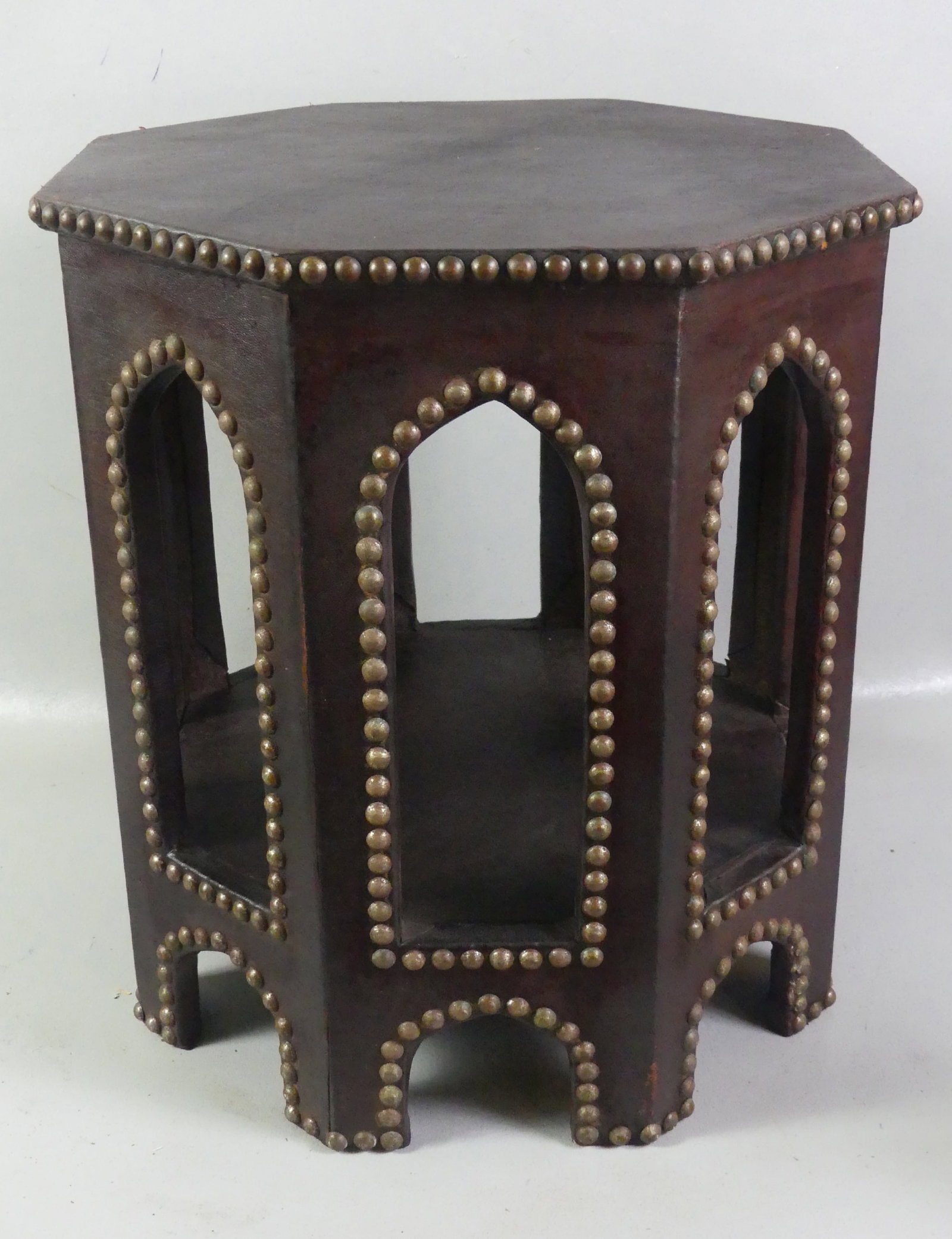 LEATHER COVERED GOTHIC TABLE: Old leather covered wood octagonal-shaped Arts and Crafts period occasional table with studded tack decoration. Top is 19 in, 20 in high. Note: We can ship this in-house.