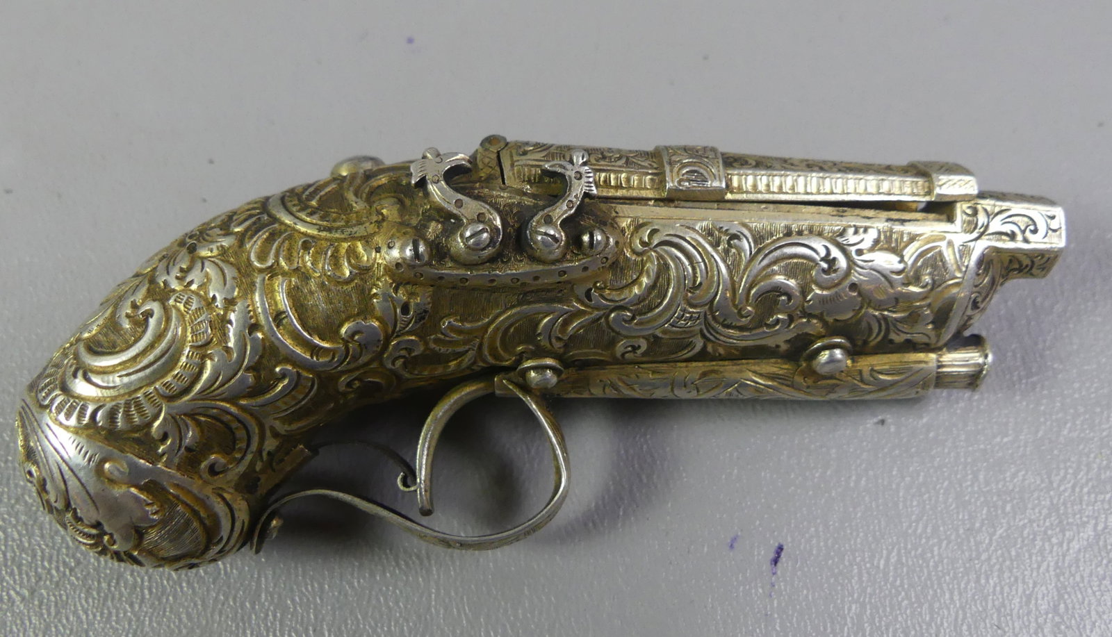 ANTIQUE SILVER PISTOL-FORM SNUFF BOX: 19th century rococo silver snuff box in the form of an 18th century double-barreled flintlock pistol having hinged lid that opens when the trigger is squeezed. 4 in long, fancy chased designs,