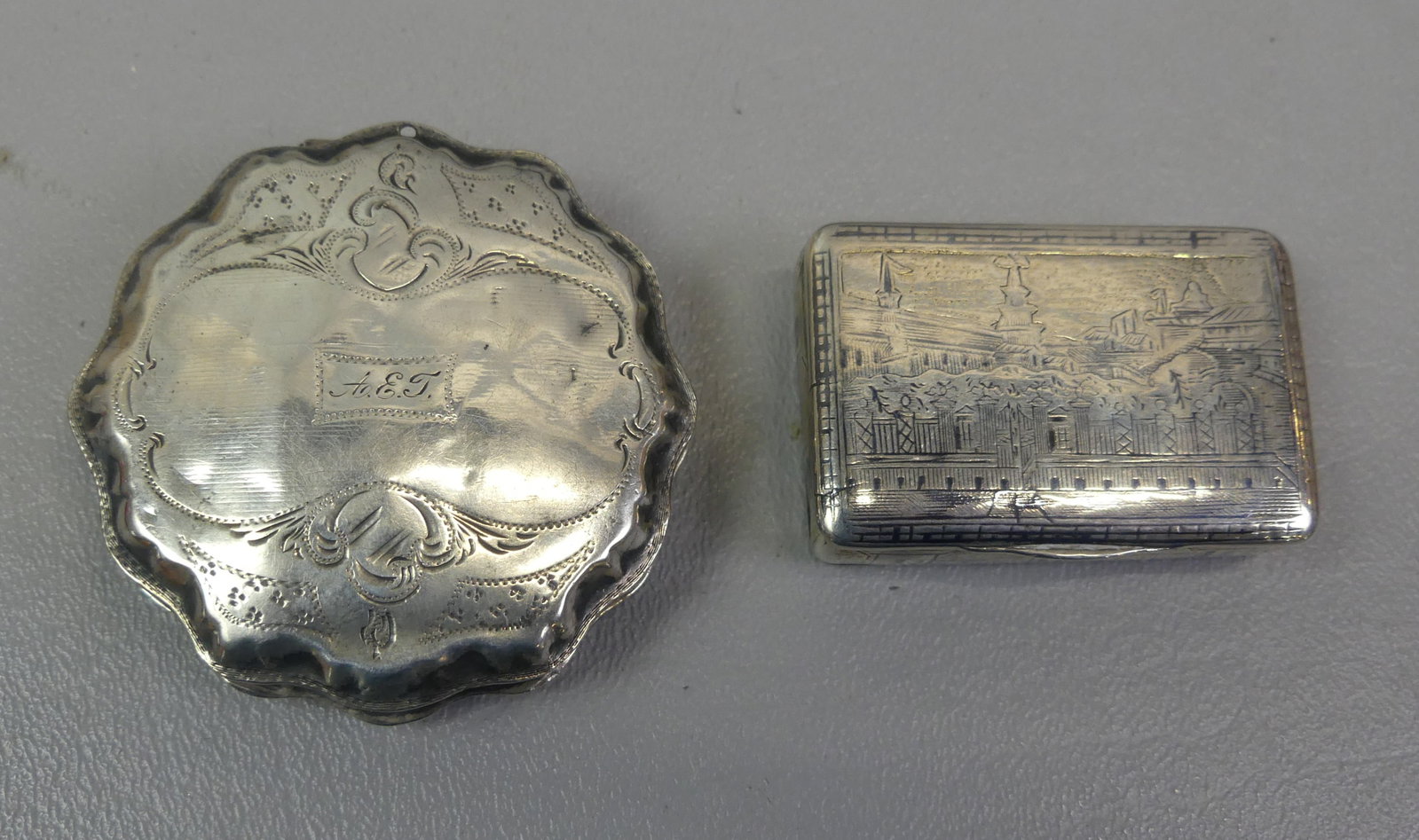 2 SILVER SNUFF BOXES - 1 RUSSIAN: Lot of 2 antique silver snuff boxes: Russian 84 mark engraved with buildings on all sides, 2 x 1.25 x 0.5 inches; and continental roound scalloped and engraved box, 2.25 x .05 in thick. Total 68.6