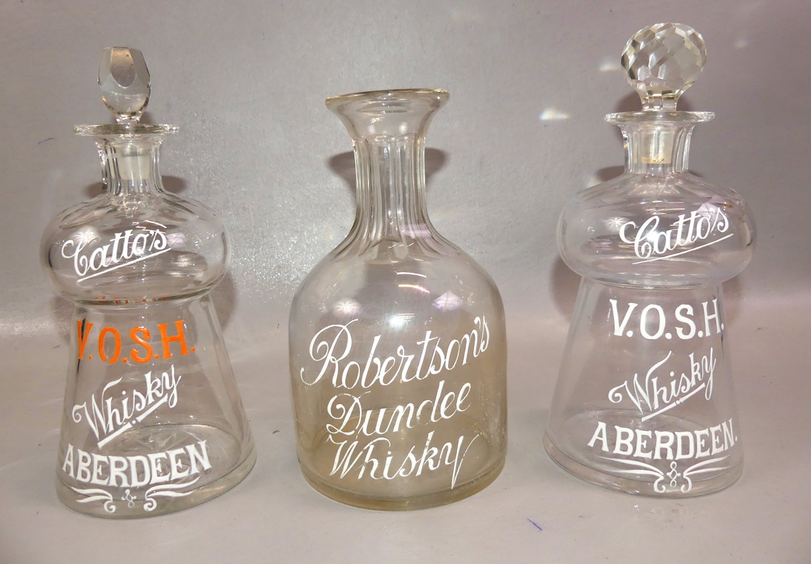 CATTO'S & ROBERTSON WHISKY AD BOTTLES: Lot of 3 scarce English Whisky blown and cut glass advertising bottles with enamel: Pair of Catto's VOSH Whisky, Aberdeen decanters, 8 in high (not including replaced stoppers). Plus a Robertson's