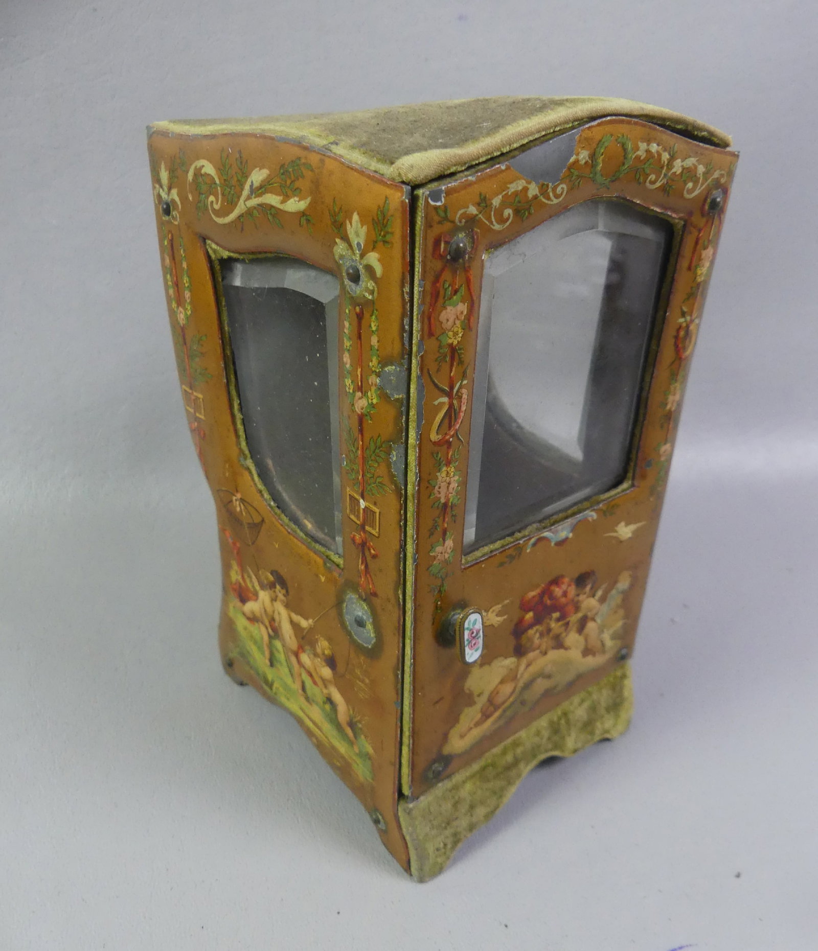 FRENCH SEDAN CHAIR WATCH HOLDER: Charming 19th century French watch holder in the form of a sedan chair with painted classical cherubs on metallic sides with beveled glass windows, green felt interior and back. Enameled door handle