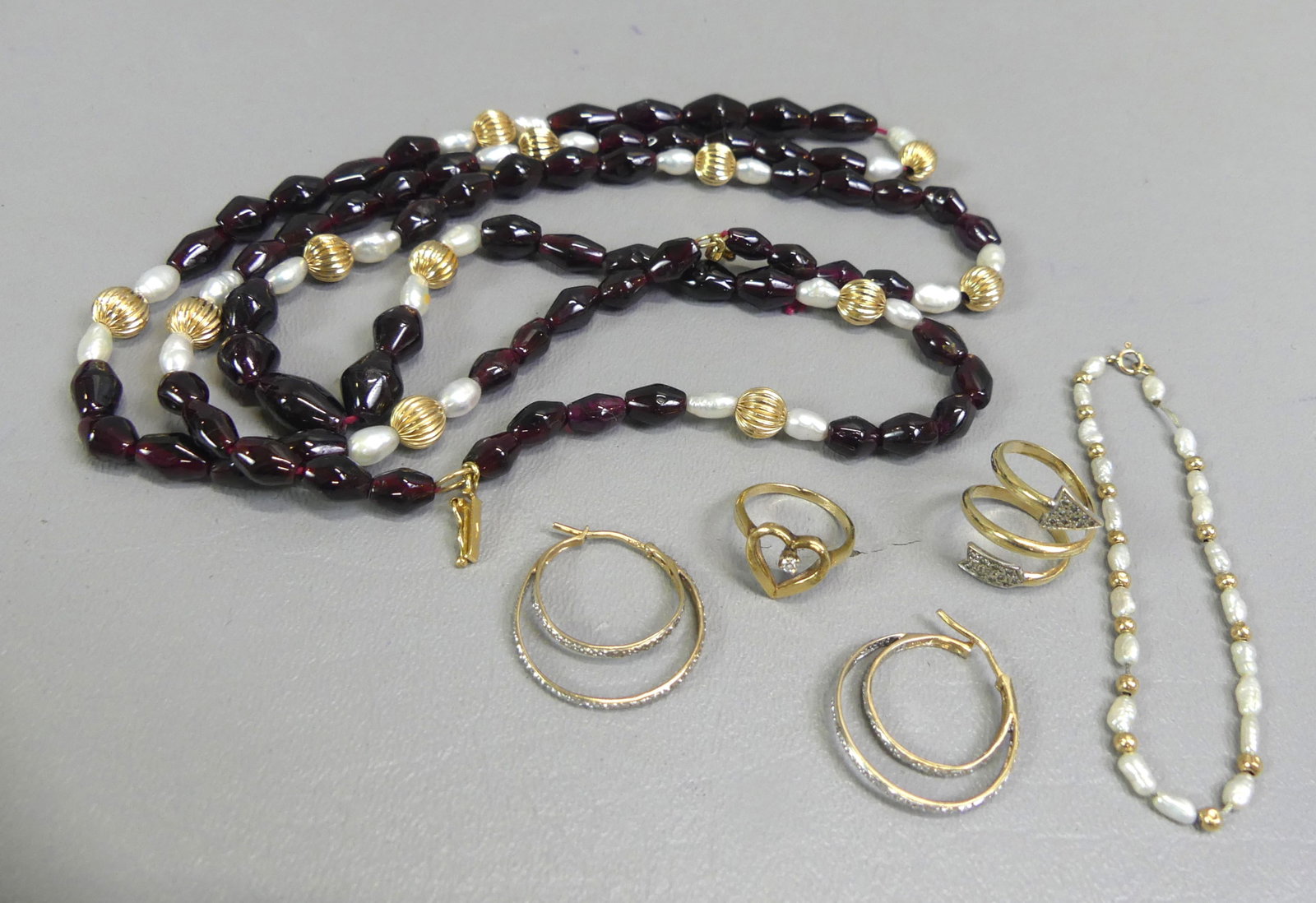 GROUP OF 14K GOLD JEWELRY: Group of 14k gold jewelry: 38 inch Italian necklace set with garnets and pearls; small braclet with pearls; 2 rings - heart shape size 5 and arrow-form size 4; pair of double-loop earrings. Total