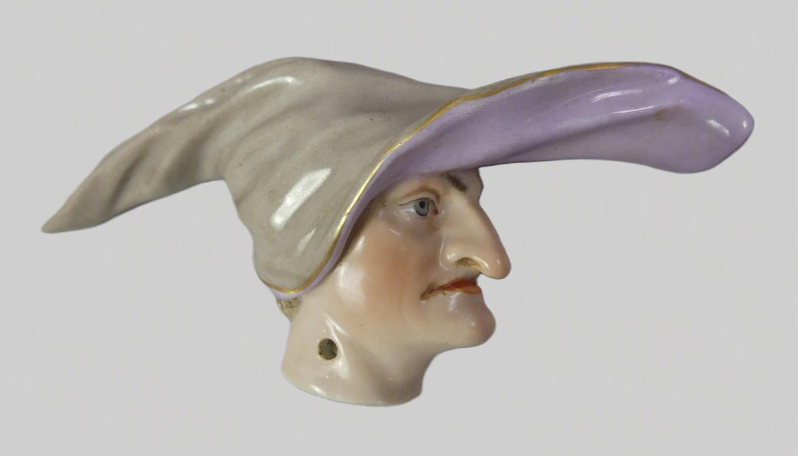 MEISSEN CANE HANDLE - HEAD OF A MAN: Rare 19th century Meissen figural porcelain cane handle in the form of a long-nosed man with elongated hat, probably modeled after a player in the Italian Commedia Dell'Arte. Has underglaze crossed