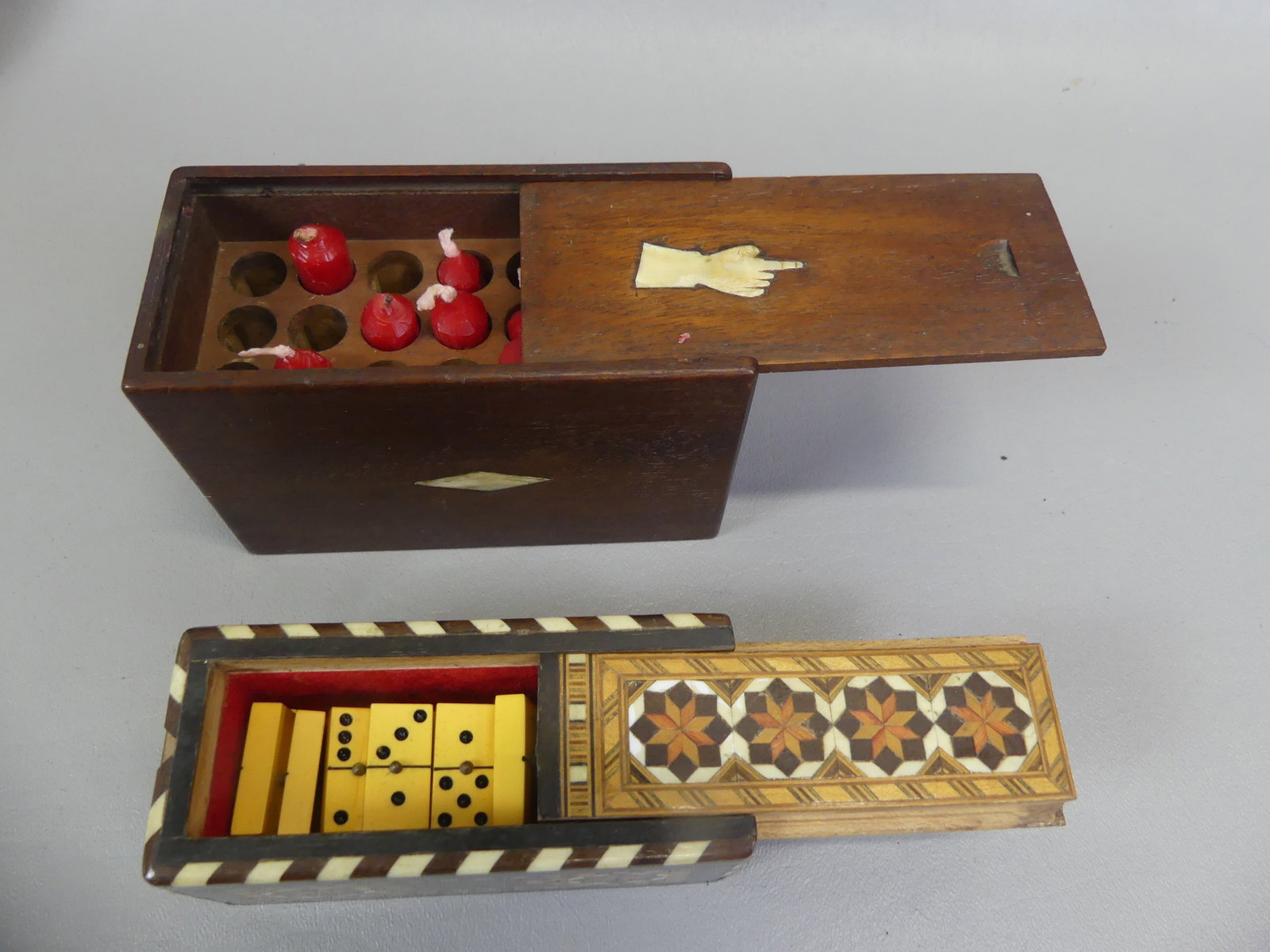 2 BOXES: MINI CANDLES & DOMINOES: Lot of 2 nice antique boxes: 19th century miniature candle box (12 holes) in walnut inlaid with bone having human hand and geometric designs, 4.75 x 3 x 2 inches; and old marquetry inlaid game box wit