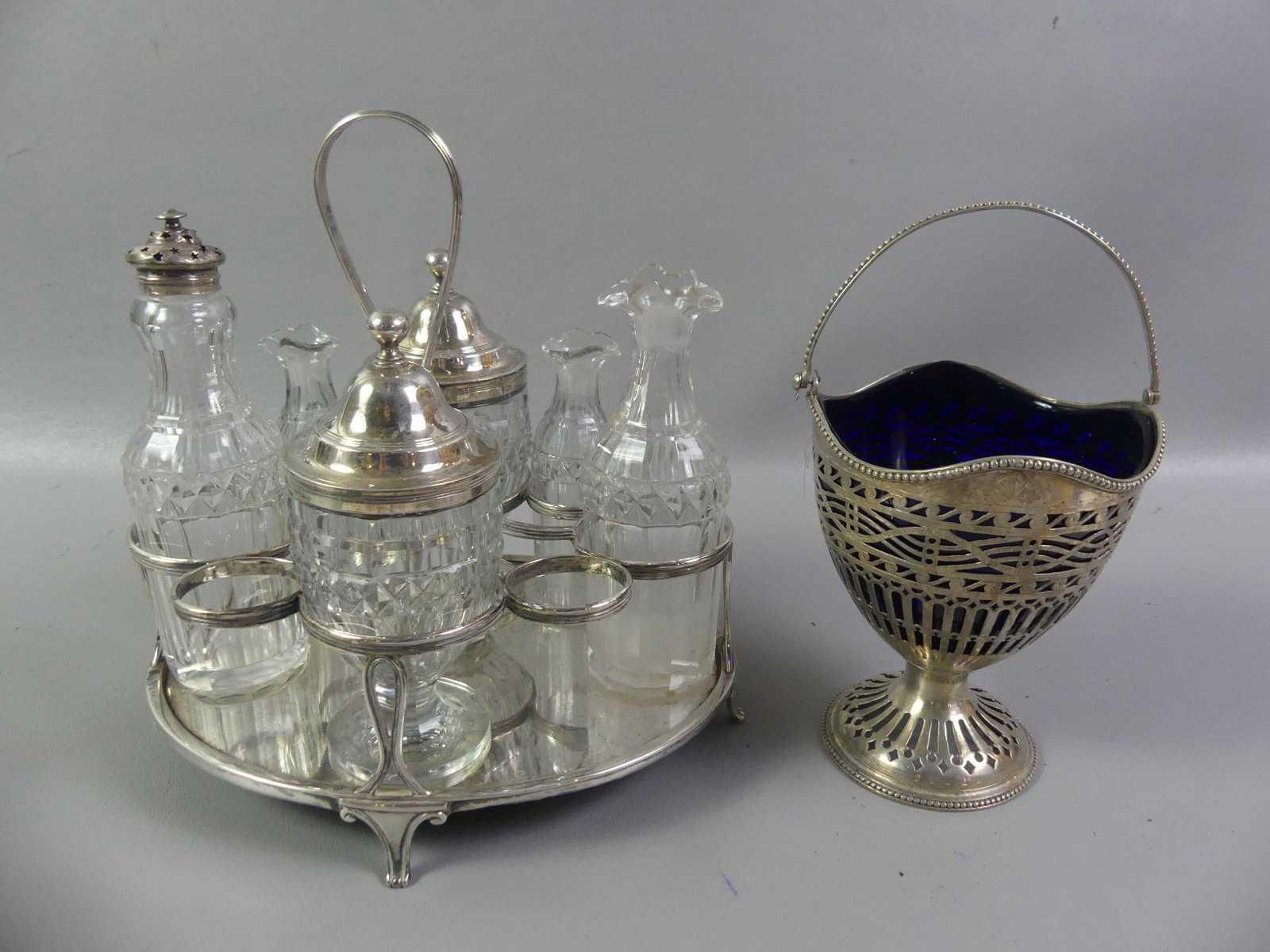 ENGLISH STERLING CASTOR SET & BASKET: Lot of 2 items: English sterling silver castor set with wood base having 6 cut glass bottles (2 missing) with sterling silver tops. Hallmarks for London 1804 maker BH/SH. Base weighs 17.3 ozt; and a