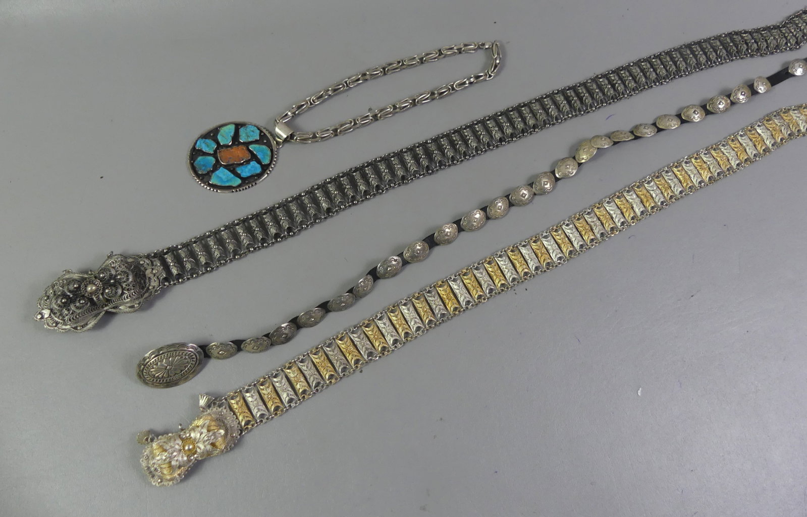 3 SILVER BELTS & NAVAJO NECKLACE: Lot of 4 silver items: Heavy Navajo sterling silver 18 in necklace with large 3.25 inch oval pendant with inset turquoise and coral; 2 fancy filigree silver belts with elaborate buckles, one