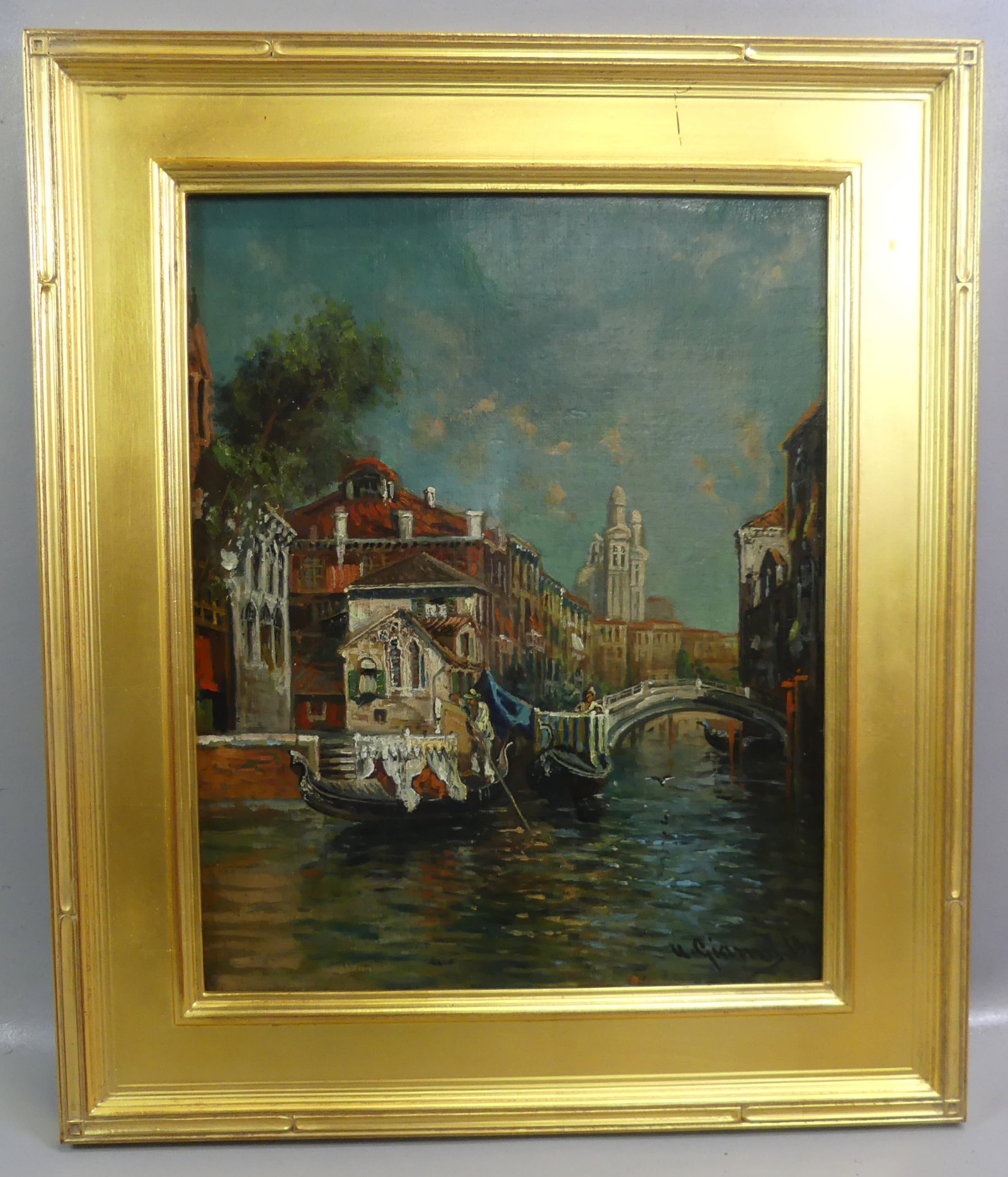 U. GIANNI 1910 - VENETIAN OIL PAINTING: Antique oil painting on canvas depictging a Venetian canal scene with gondolas, bridge, and buildings signed U. Gianni 1910. 20 x 16 in, framed 26 x 22 in. (Ugo Gianni b. 1876 Malta, active 1905-1918