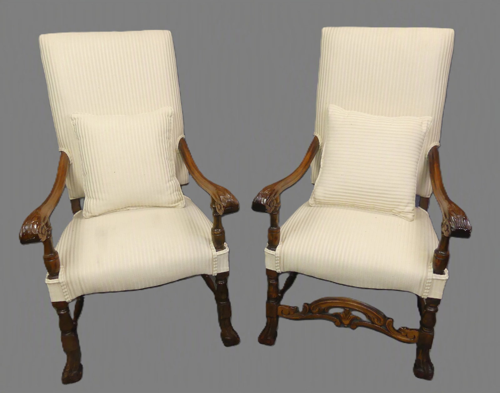 PAIR OLD WALNUT LOUIS XIII ARMCHAIRS: Pair of old carved walnut tall-back Louis XIII style armchairs with Spanish feet, one missing front stretcher. Clean, cream-colored upholstery with 2 pillows. 45 in tall x 26 w x 20 in deep.